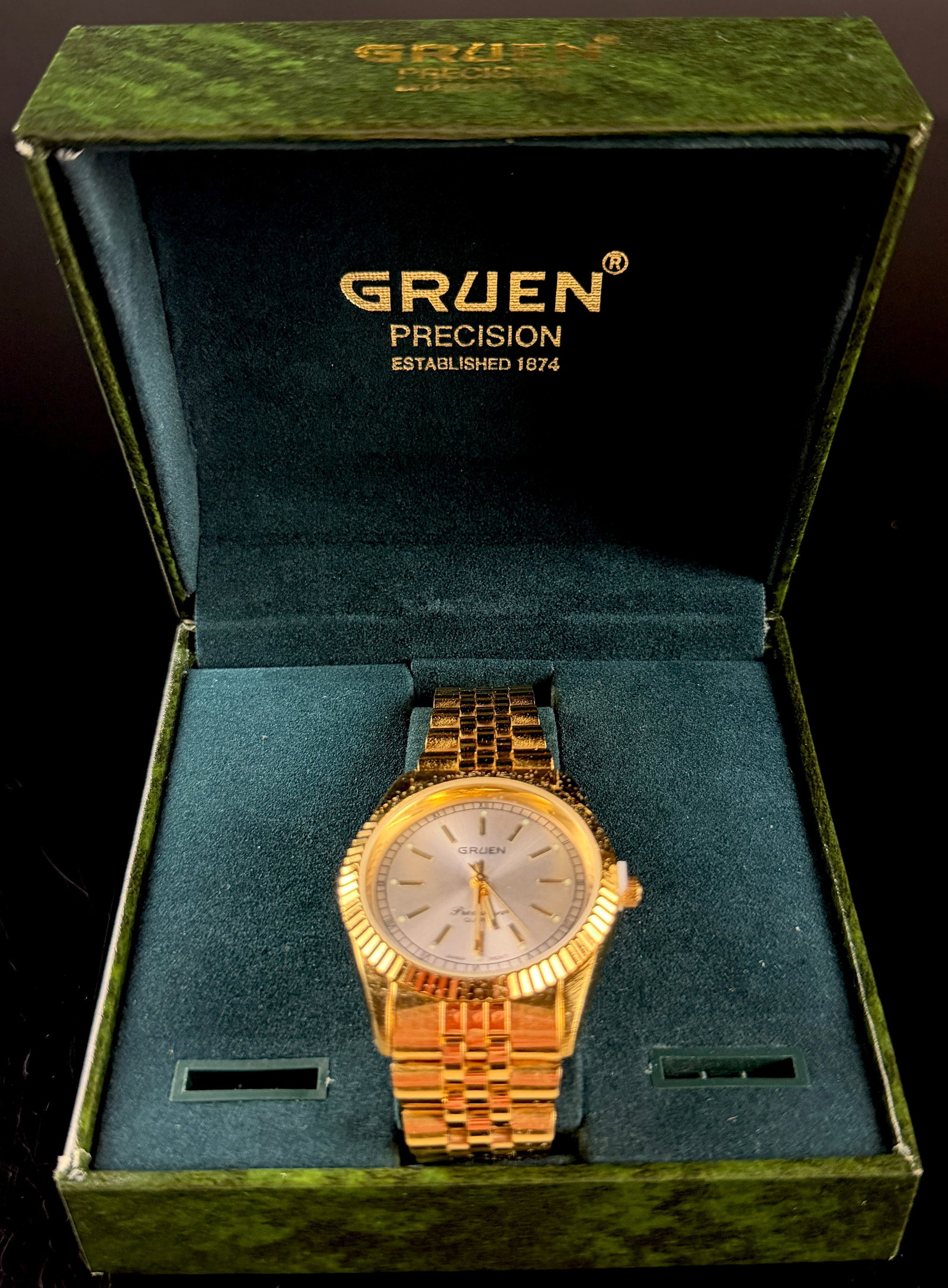 Gruen Precision Gold-Tone Quartz Wristwatch with Box and Papers: A Gruen Precision gold-tone wristwatch featuring a classic design with a fluted bezel and integrated jubilee-style bracelet. The timepiece has a sunburst silver-tone dial accented by applied gold-tone