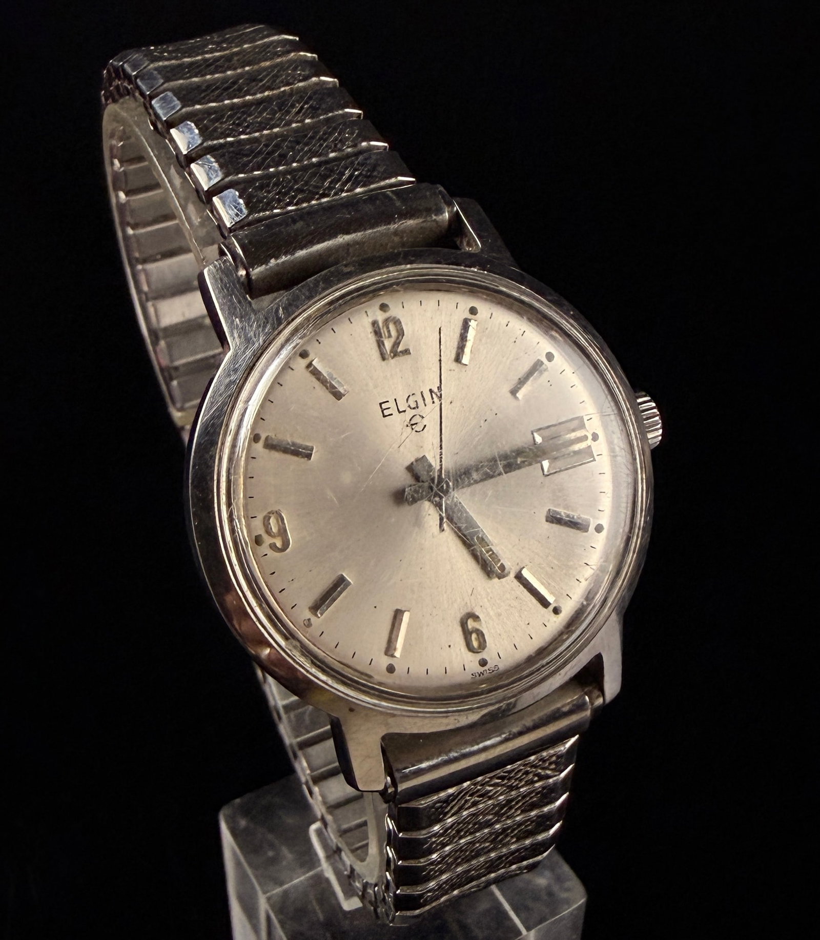 Vintage Elgin Stainless Steel Swiss Manual Wind Date Wristwatch: This vintage Elgin wristwatch features a Swiss-made manual wind movement. The silver-tone sunburst dial is detailed with applied silver-tone baton hour markers, Arabic numerals at the 12, 6, and 9 pos