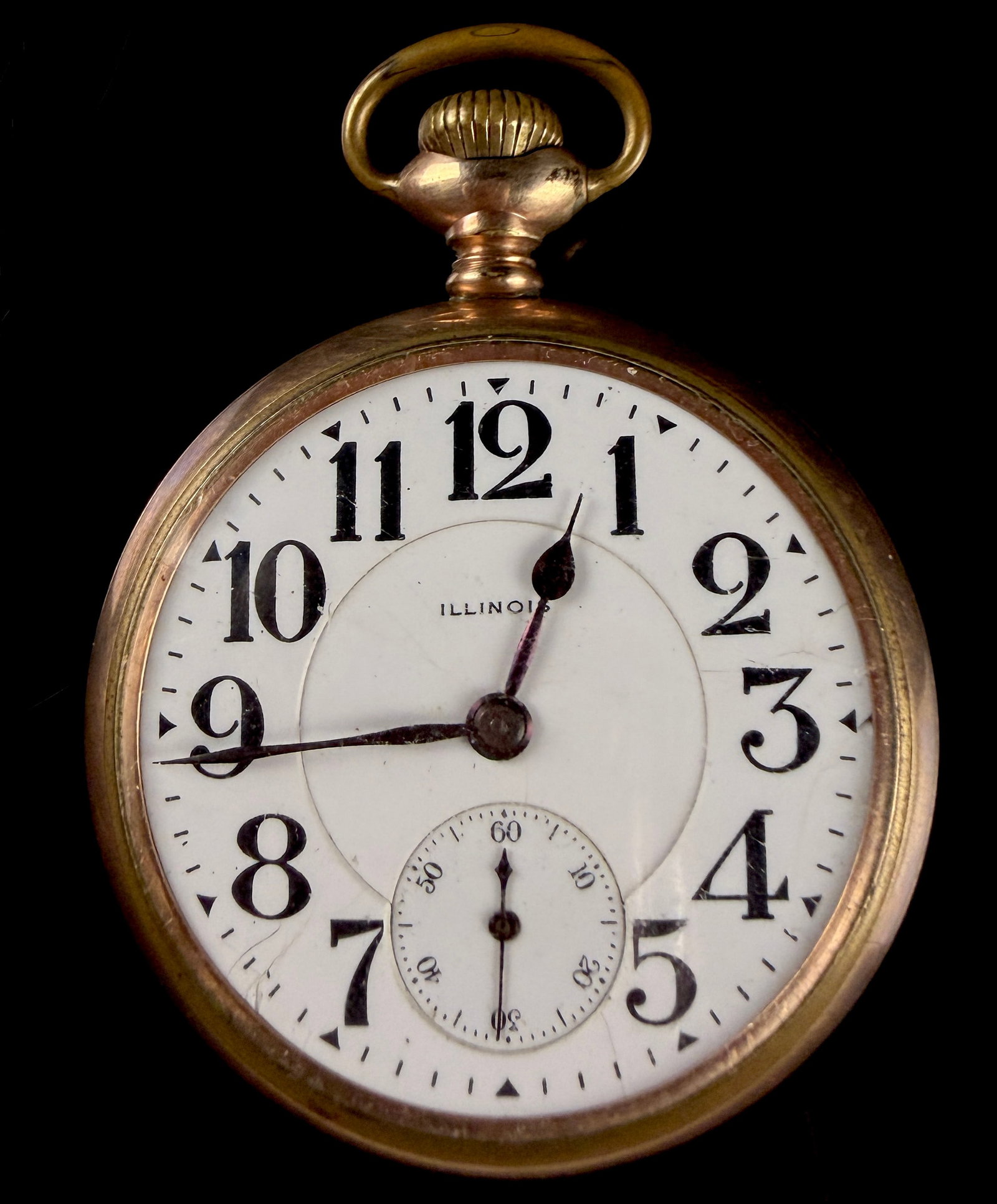 Illinois 16-Size Gold-Filled Open-Face Pocket Watch: An antique open-face pocket watch manufactured by the Illinois Watch Company. The watch features a gold-filled case with an engraved decorative monogram on the case back. The white porcelain enamel di