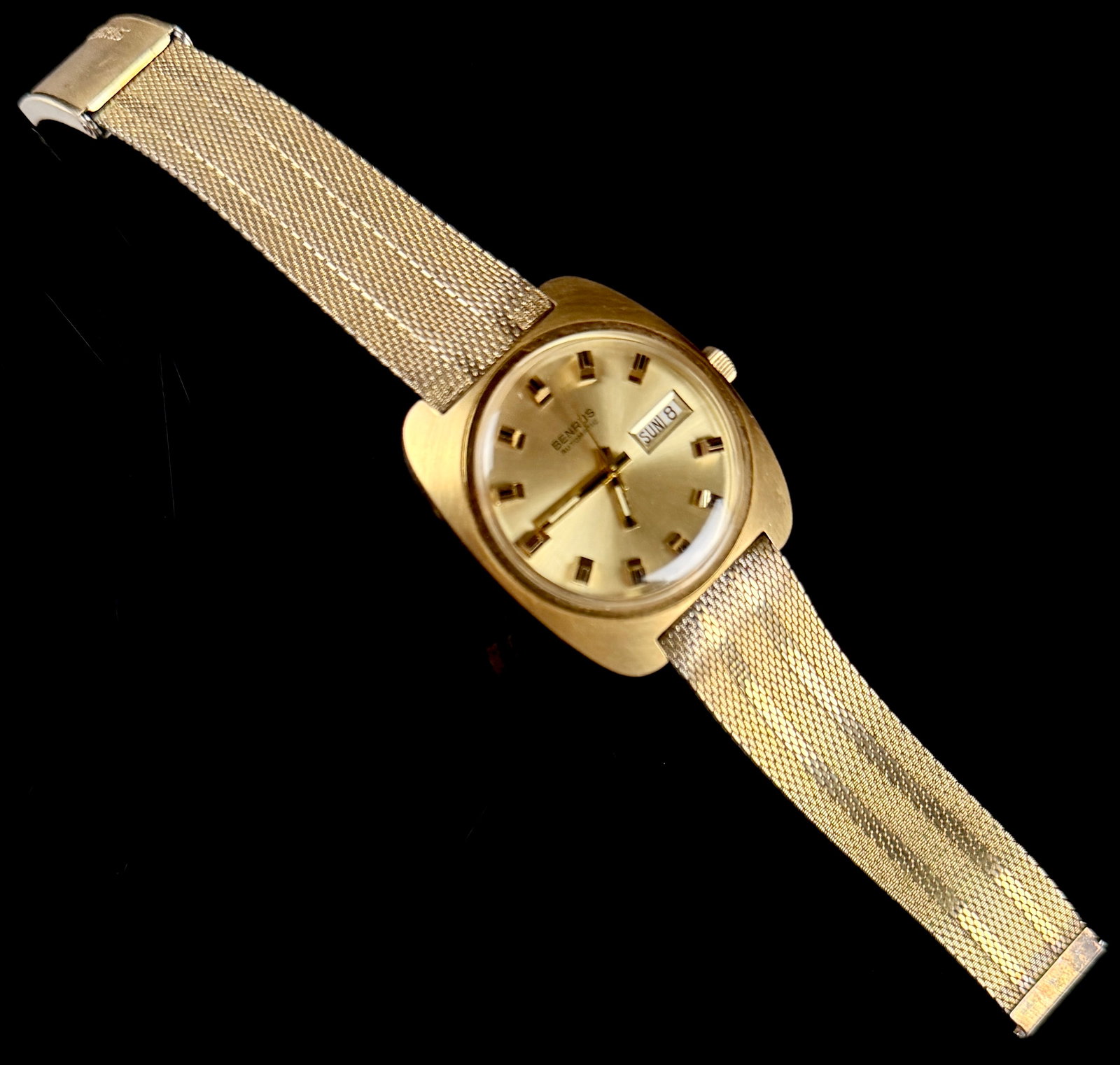 Vintage Benrus Automatic Day-Date 14K Gold Electroplate and Stainless Steel Wristwatch: This vintage Benrus automatic wristwatch features a cushion-style case with a 14 karat gold electroplated bezel and a stainless steel case back. The sunburst champagne dial is set with applied gold-to