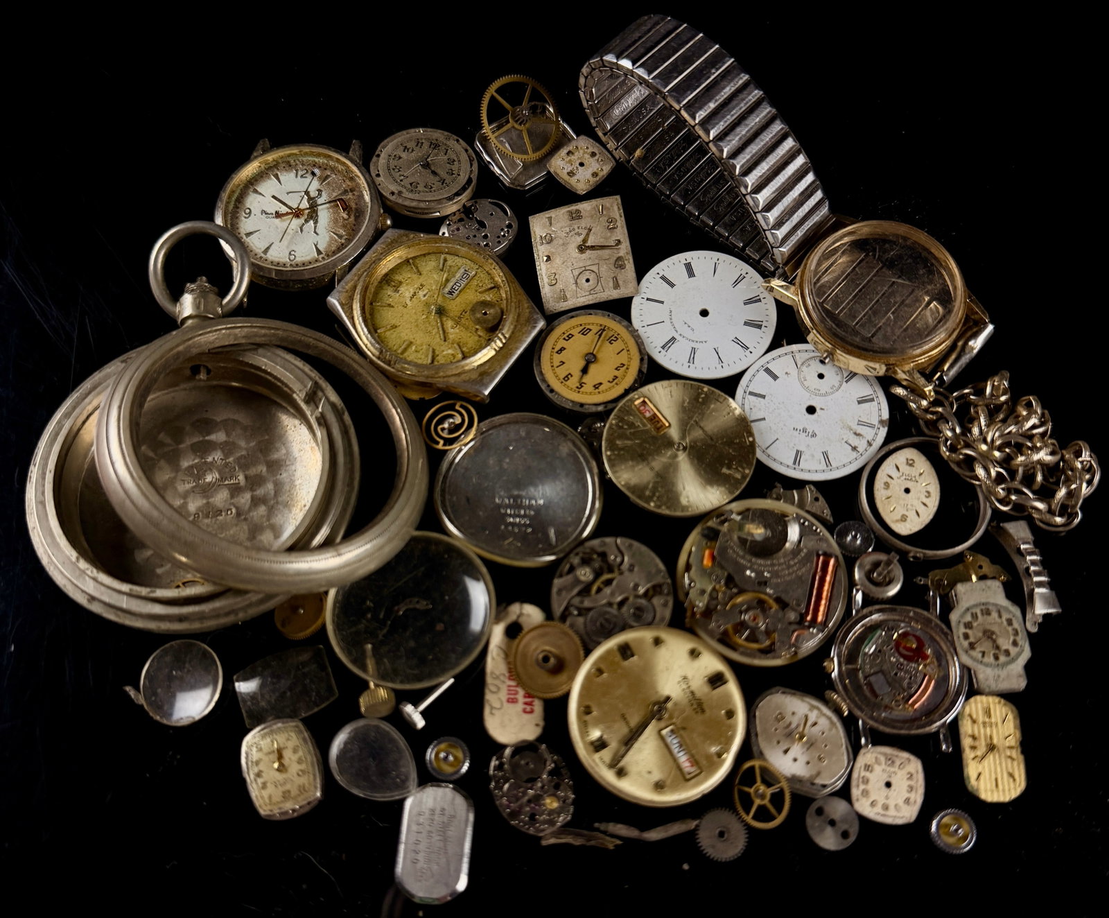 Assortment of Vintage Watch Parts and Movements Including Hamilton, Waltham, and Elgin: This collection contains an assortment of vintage watch components, movements, and cases suitable for repair salvage or horological study. The lot includes parts from several prominent manufacturers s