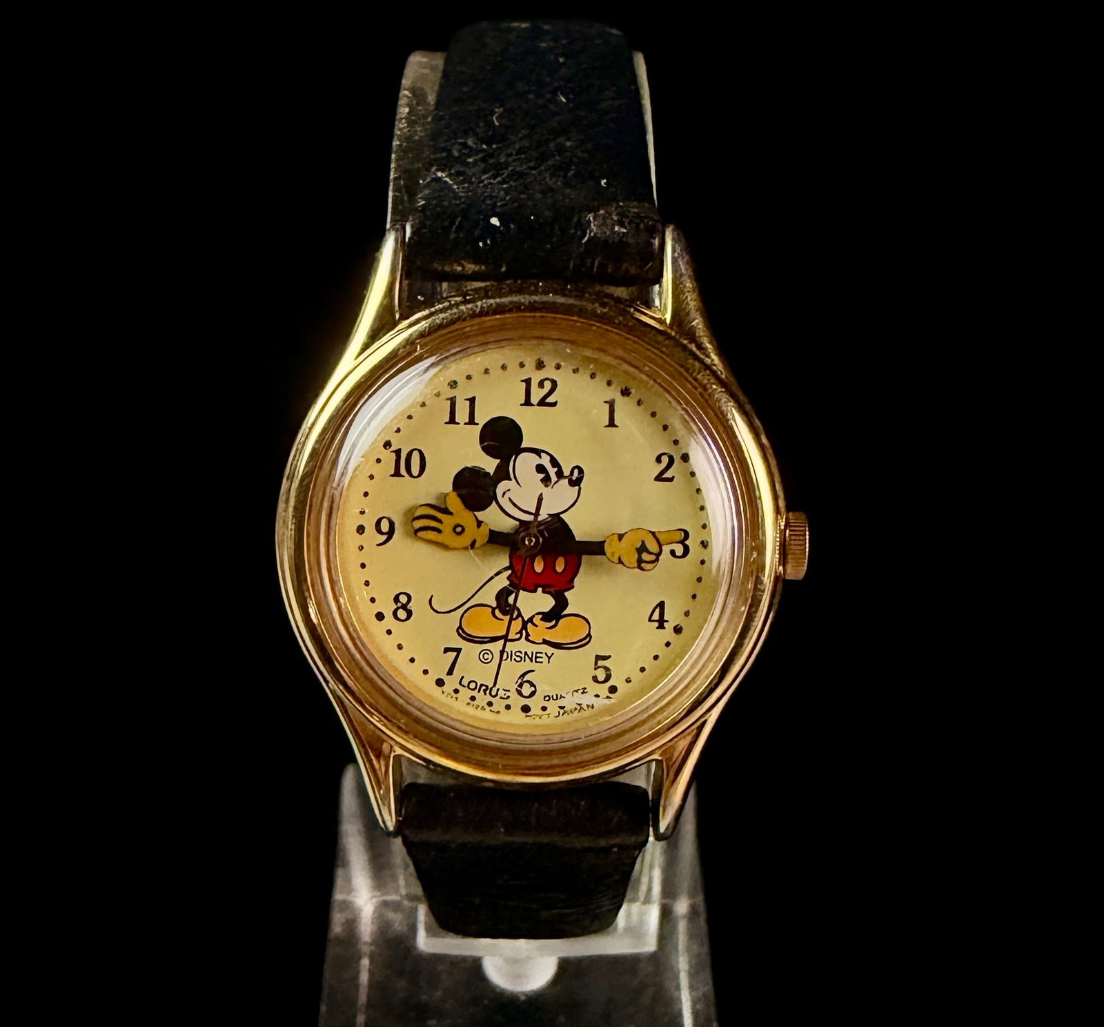 Lorus Disney Mickey Mouse Quartz Wristwatch V515-6080: This vintage Lorus Disney Mickey Mouse wristwatch features a yellow dial with a full-color character illustration where the articulated arms of Mickey Mouse serve as the hour and minute hands. The wat