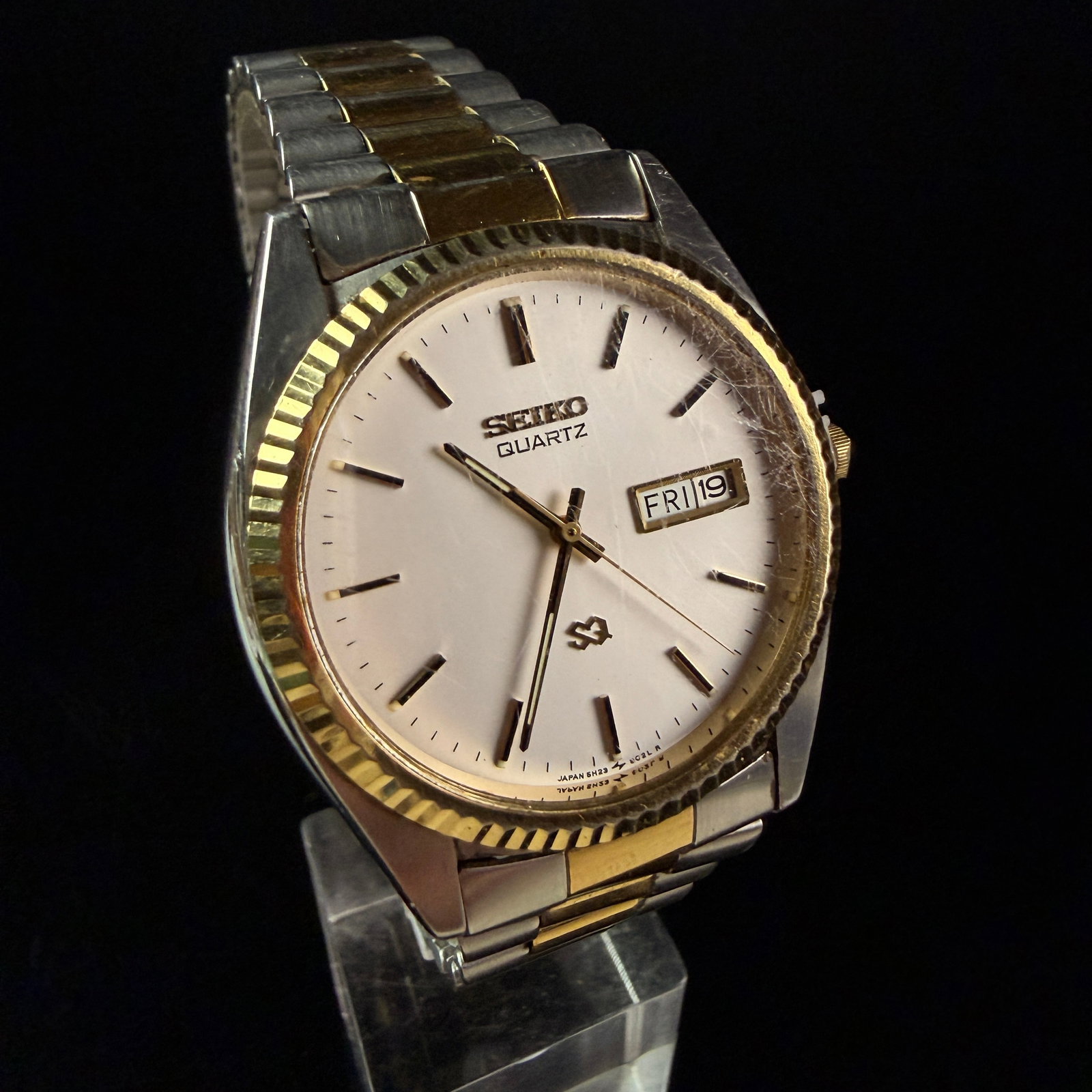 Seiko SQ Quartz Two-Tone Day-Date Wristwatch Reference 5H23-8029: A vintage men's Seiko SQ Quartz wristwatch featuring a classic two-tone aesthetic. The timepiece is constructed with a stainless steel case and case back, topped with a fluted gold-tone base metal bez