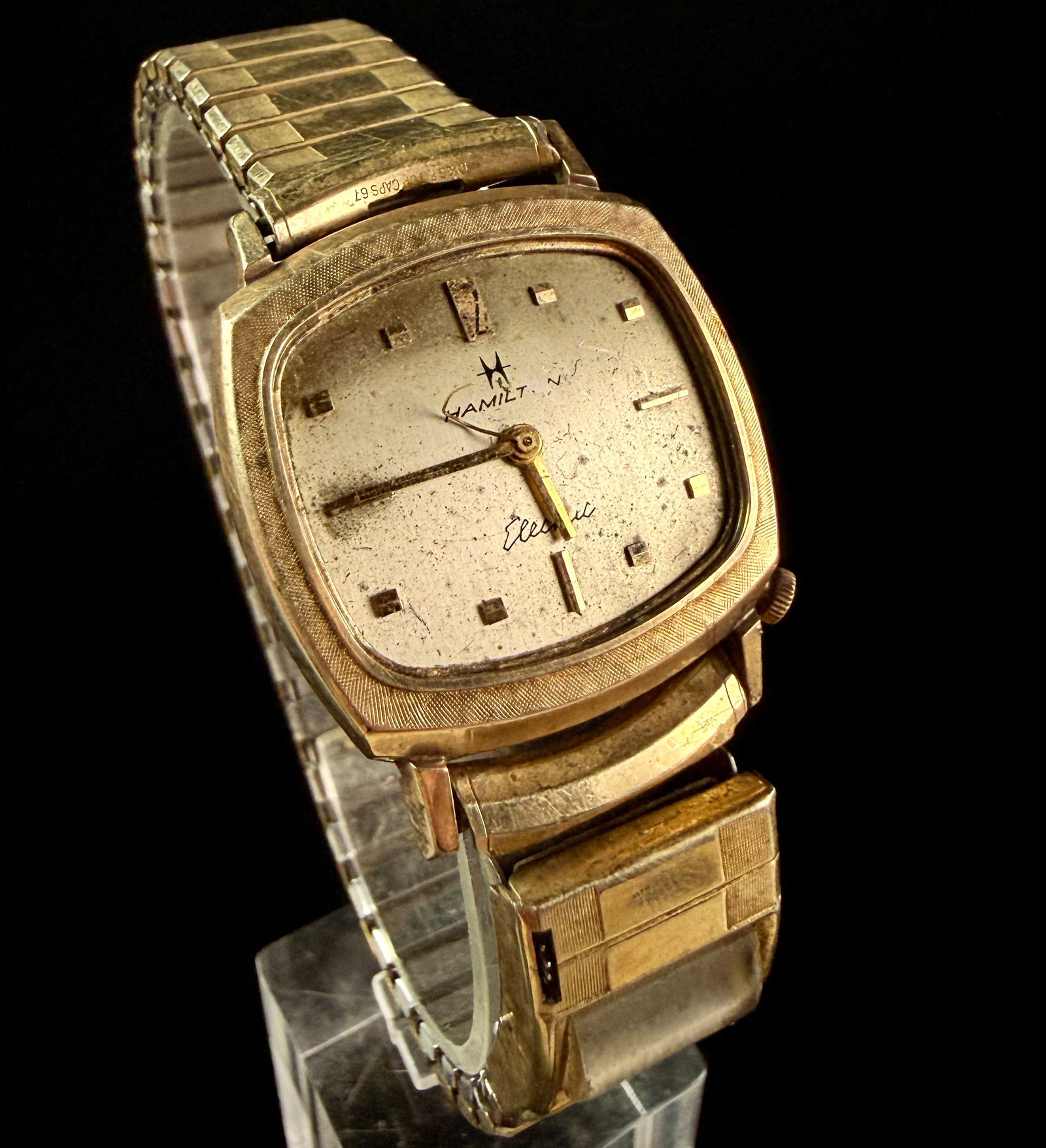 Hamilton Electric Vela 10K Rolled Gold Plate Wristwatch with Speidel Calendar Bracelet: This is a vintage Hamilton Electric Vela wristwatch, featuring a 10K rolled gold plate square tonneau-shaped case with a distinctively textured bark-effect bezel. The dial is a cream tone set with app