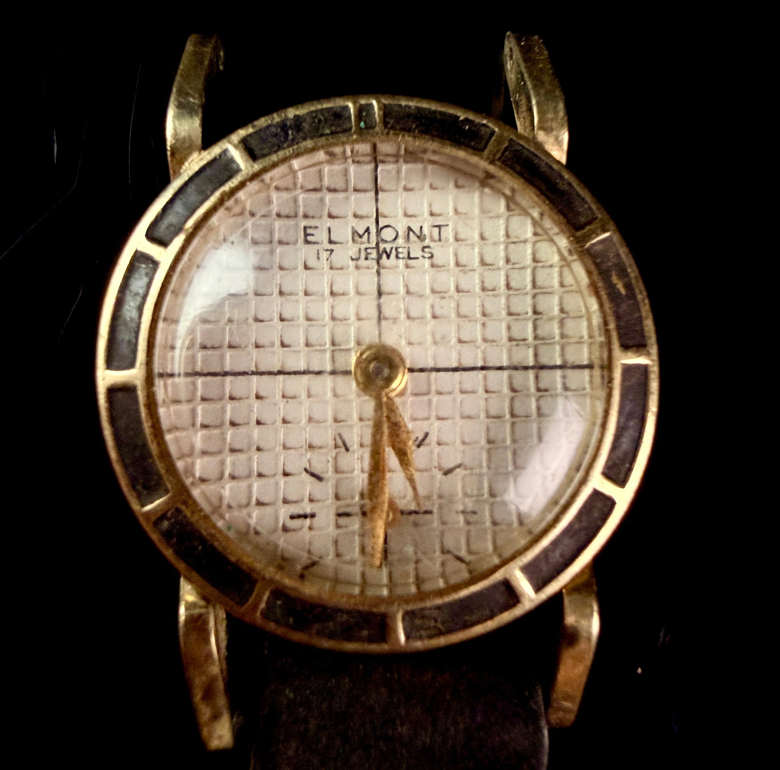 Vintage Elmont 17 Jewel Wristwatch with Enamel Bezel and Waffle Dial: A vintage mid-century manual wind wristwatch branded Elmont. The watch features a 10K rolled gold plate bezel characterized by inlaid black enamel-like segments. The silver-tone dial exhibits a textur