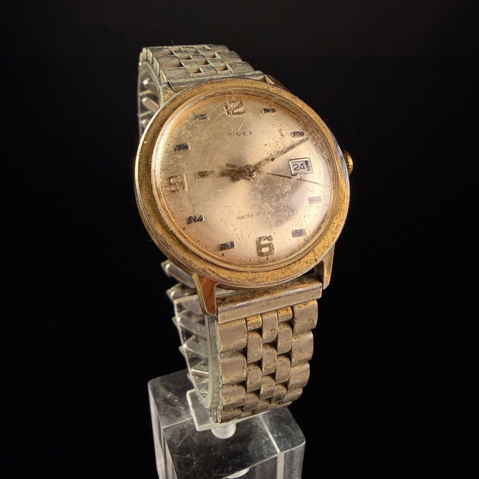 1974 Timex Marlin Mechanical Manual Wind Date Wristwatch, Reference 25410: A 1974 Timex Marlin manual wind mechanical wristwatch. The timepiece features a gold-plated base metal bezel and a stainless steel snap-on case back. The champagne-tone dial exhibits a heavy patina an