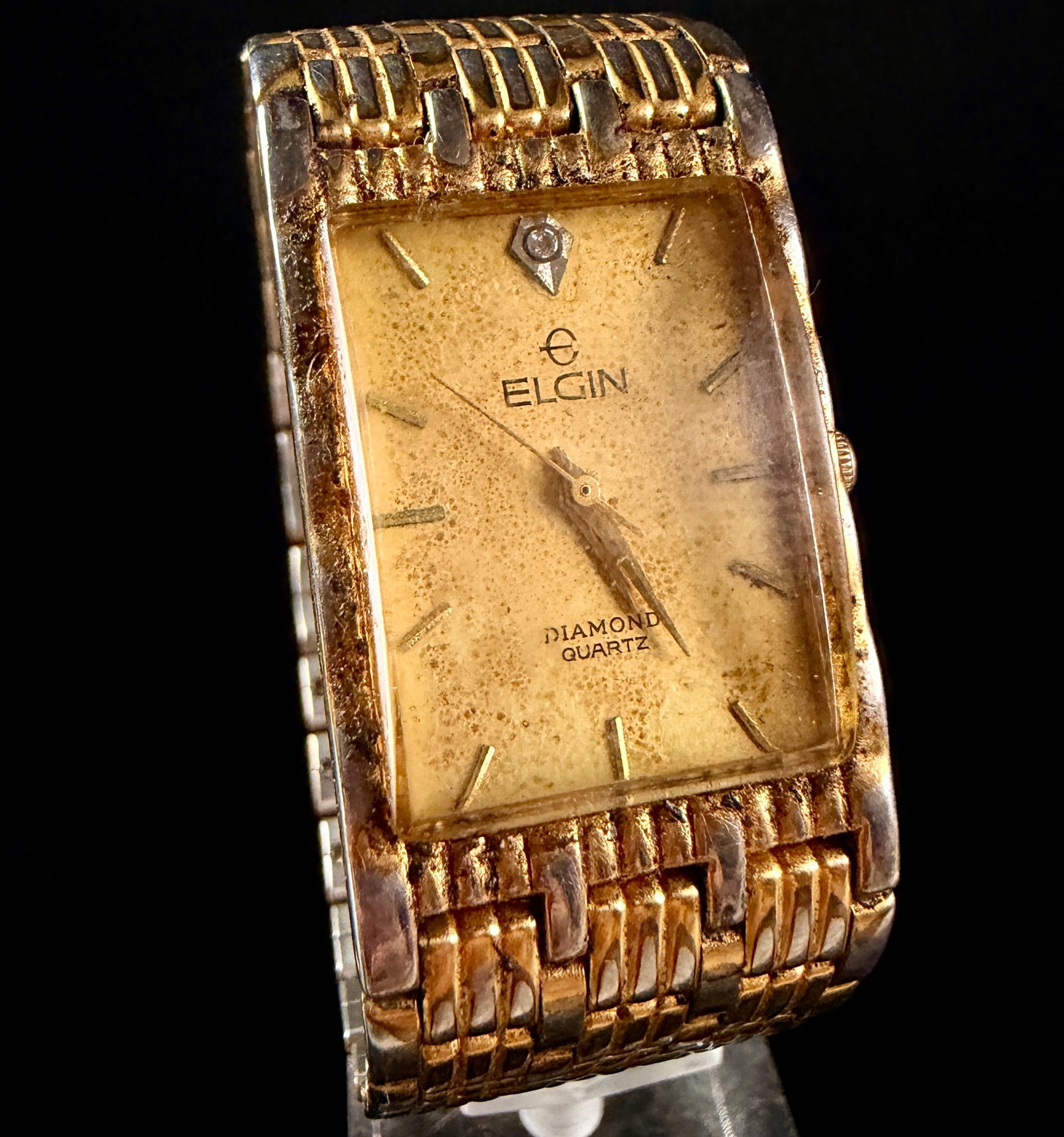 Elgin Diamond Quartz Tank Watch Reference FM1186 2035: This is an Elgin Diamond Quartz tank-style wristwatch. The timepiece features a rectangular gold-tone base metal bezel with a stainless steel case back. The champagne-colored dial displays applied gol