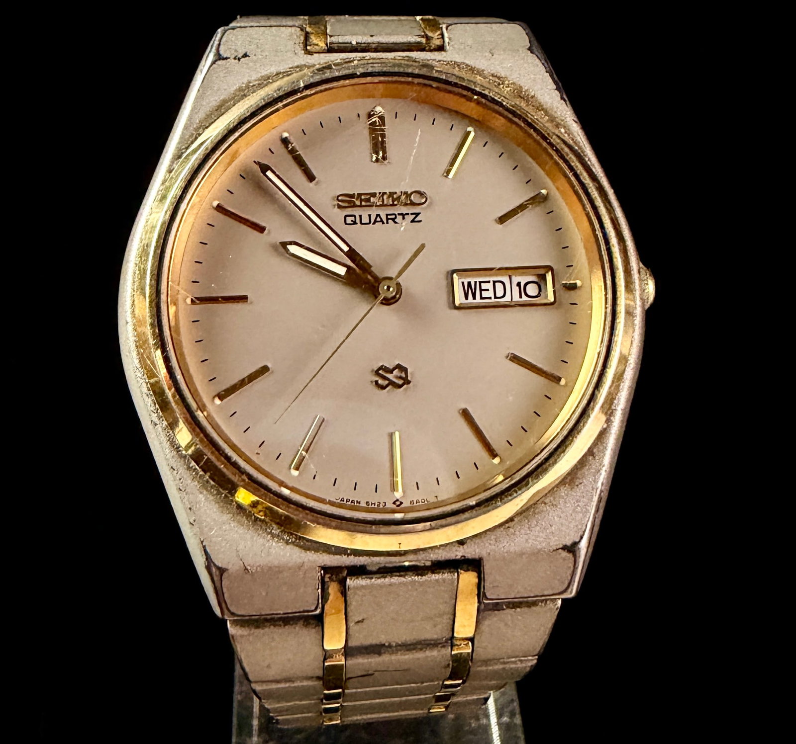 Seiko Quartz SQ Day-Date Reference 5H23-8A0L Two-Tone Integrated Bracelet Watch: This vintage Seiko SQ Quartz wristwatch features a champagne sunburst dial with gold-tone baton hour markers and a day-date aperture at the 3 o'clock position. The case is constructed of base metal