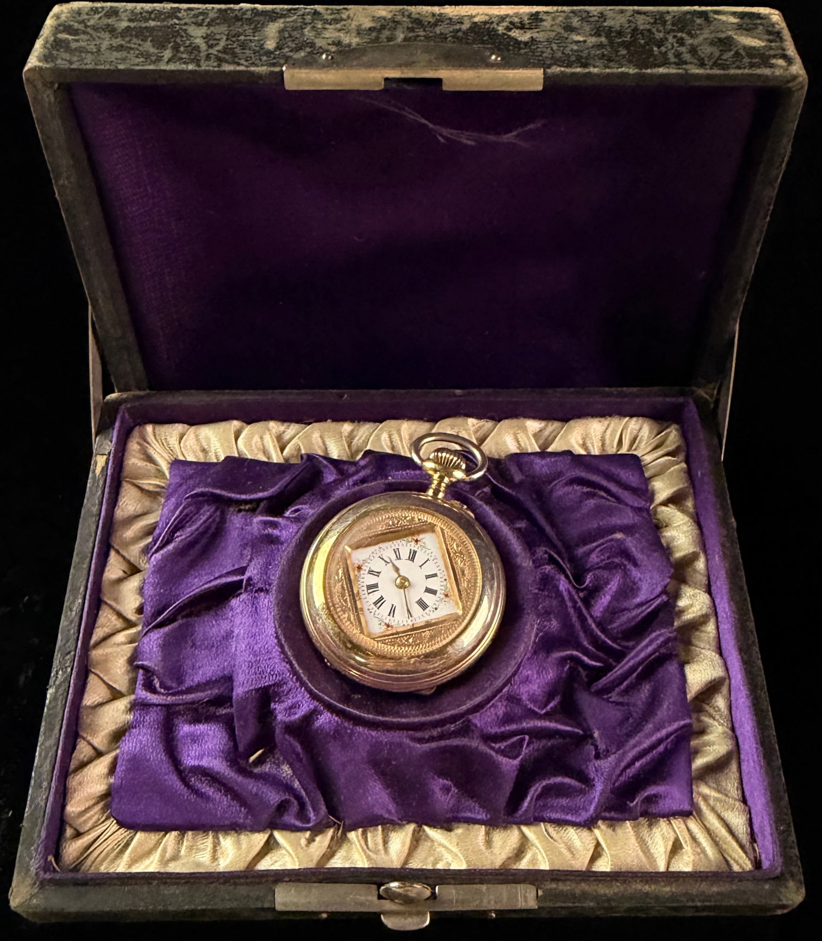 Antique Ladies Gold Toned Open Face Pocket Watch with Floral Enamel Dial and Presentation Box: An antique ladies open face pocket watch featuring a gold toned metal case. The watch is distinguished by a square white enamel dial set within a circular engraved frame. The dial is decorated with ha