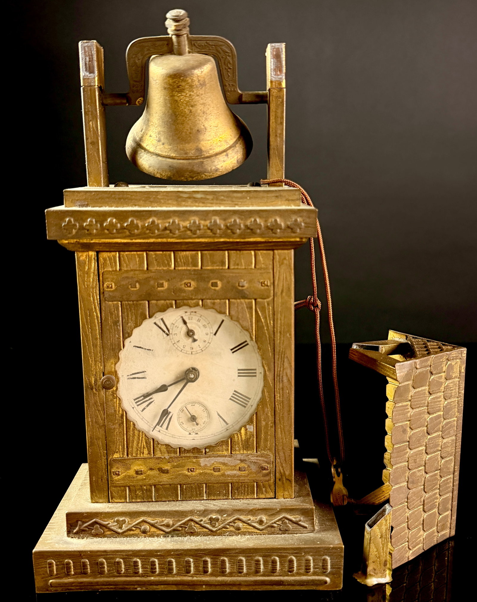 W. L. Gilbert Bell Tower Novelty Alarm Clock: An antique novelty alarm mantel clock manufactured by the W. L. Gilbert Clock Company, designed in the form of a bell tower. The case is constructed of cast metal with a gilt finish and features a tex