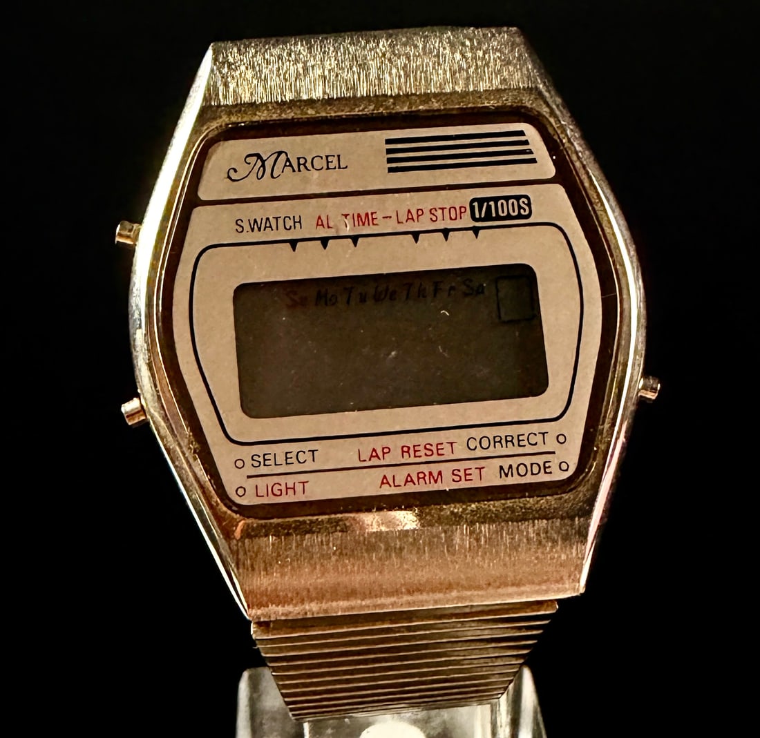 Marcel Gold-Tone Digital Alarm Chronograph Wristwatch: A vintage Marcel digital chronograph wristwatch featuring a gold-tone plated base metal case and an integrated stainless steel mesh-link bracelet. The LCD display is set within a white and gold-toned 