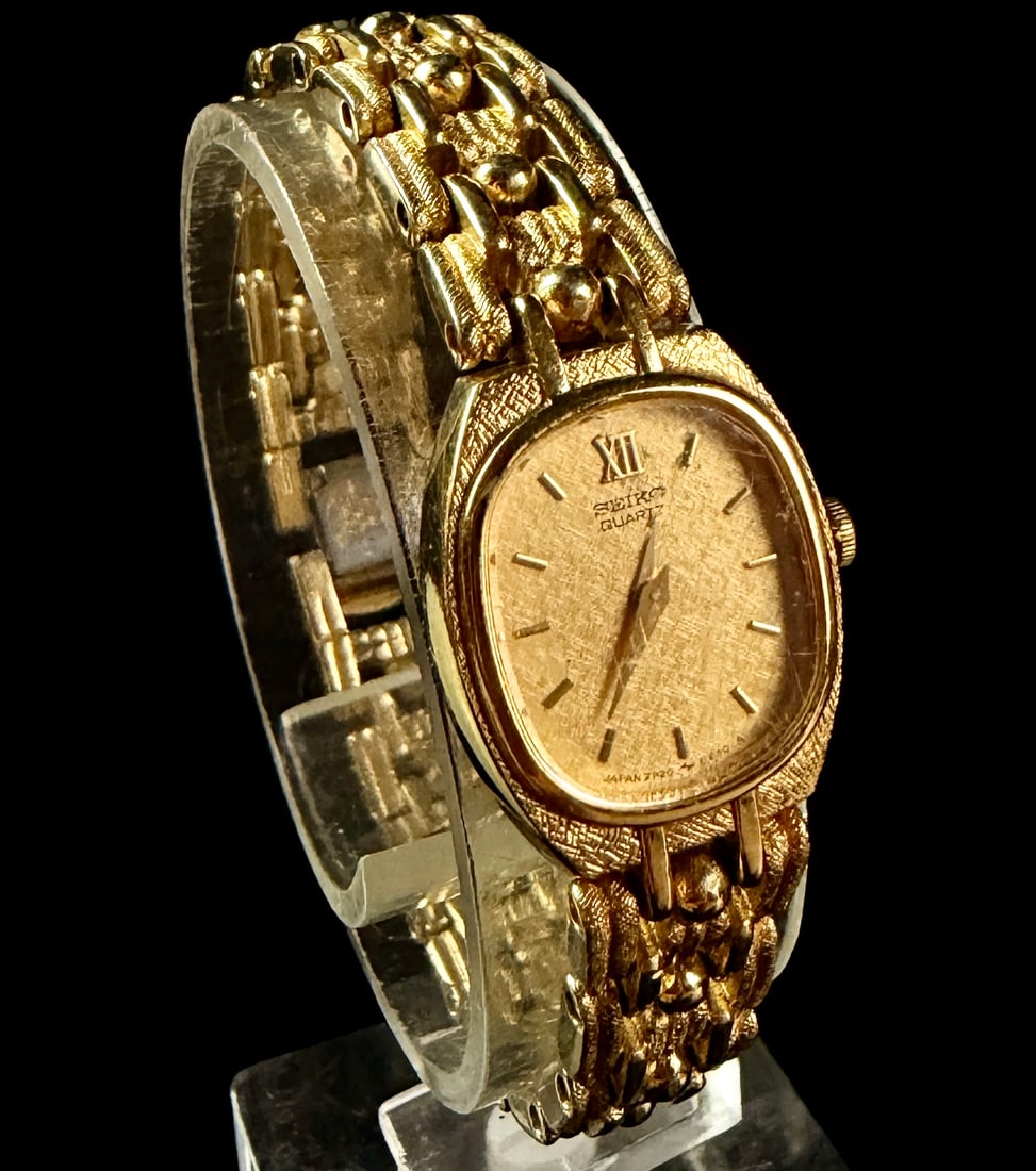 Vintage Seiko Ladies Gold-Tone Quartz Wristwatch 2P20-5329: A vintage Seiko ladies quartz wristwatch, model reference number 2P20-5329. The timepiece features a gold-tone base metal case with a stainless steel case back. The champagne-colored dial is detailed 