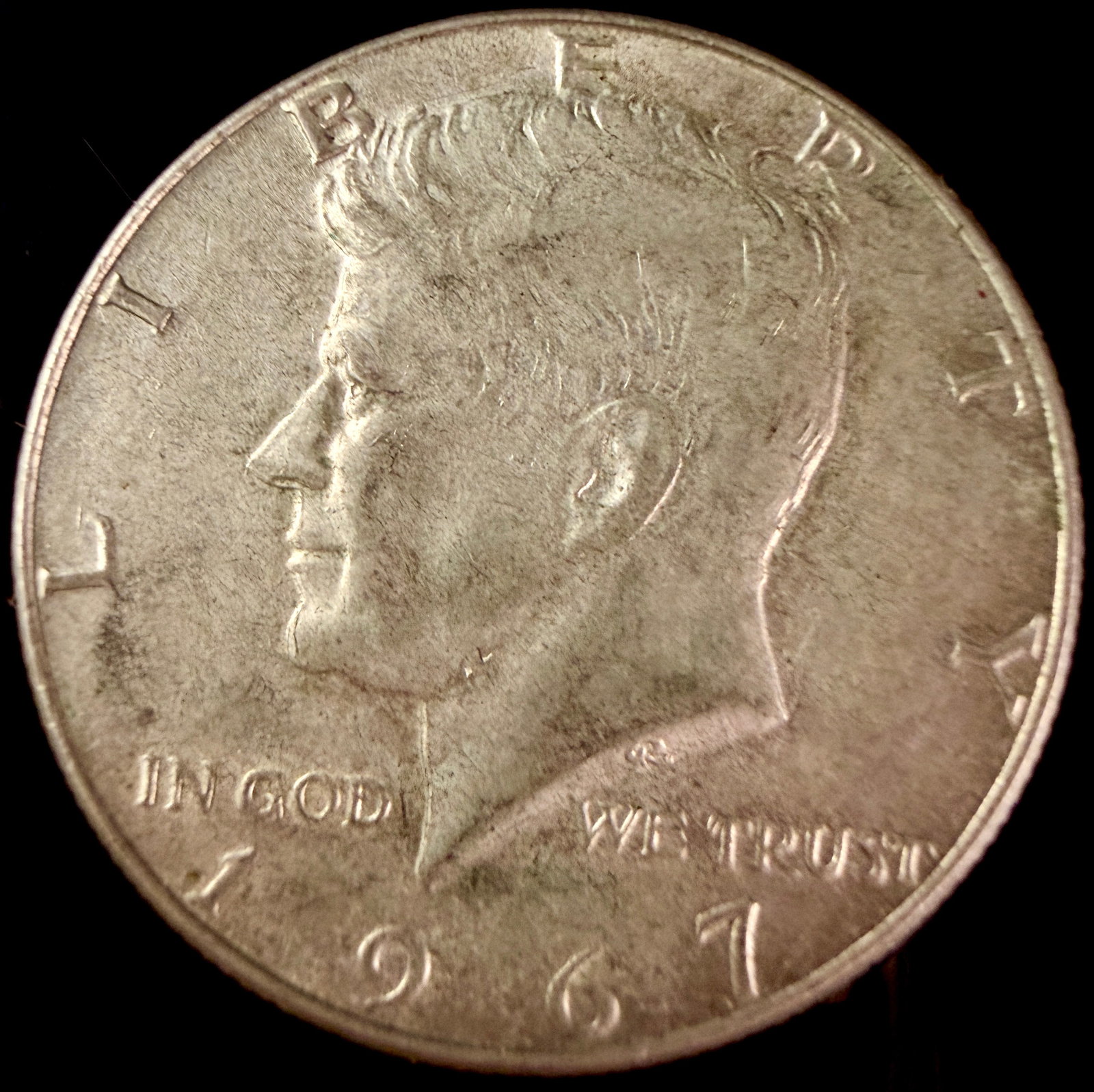 US 1967 Kennedy Half Dollar: A US 1967 Kennedy half dollar circulating coin struck in a 40% silver-clad composition. The obverse features a profile of John F. Kennedy with the designer initials GR for Gilroy Roberts readable on t