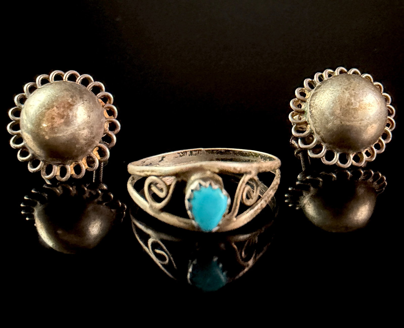 A Trio of Sterling Silver Jewelry Including a Turquoise Ring and a Pair of Domed Earrings: A sterling silver ring and a pair of matching sterling silver earrings. The ring features a teardrop-shaped blue stone that appears to be natural turquoise, secured in a sawtooth bezel setting. The ba