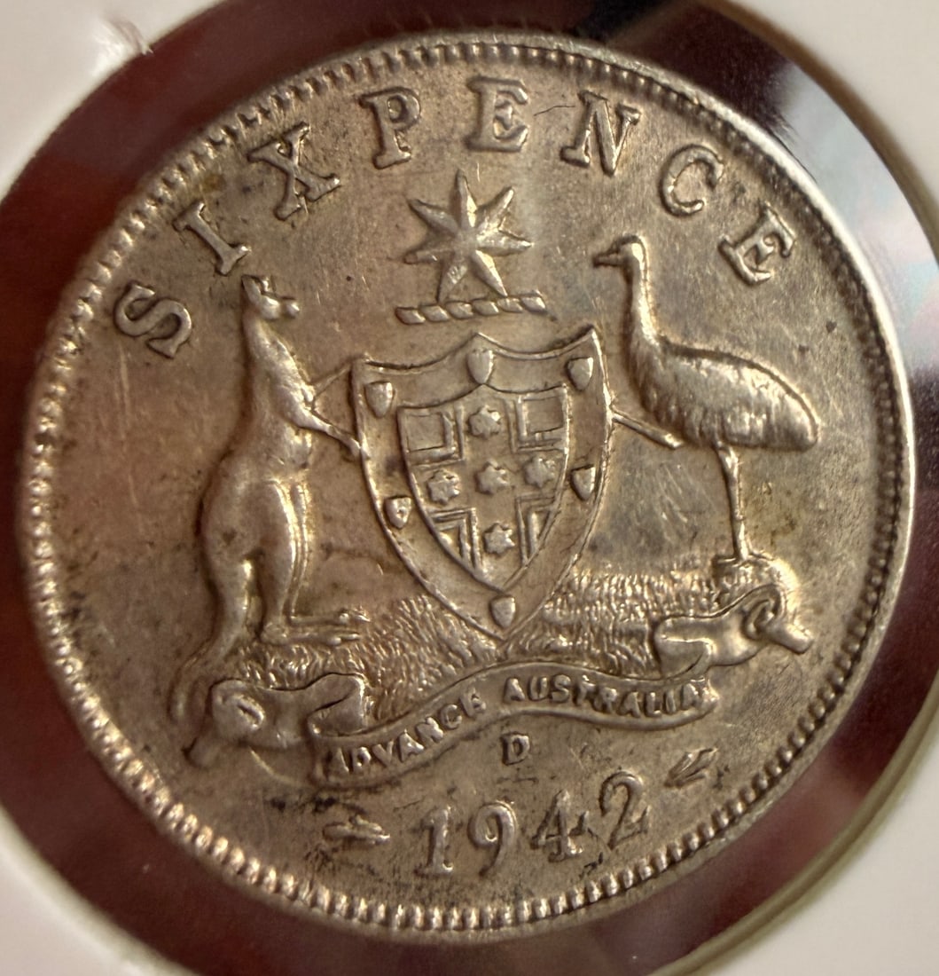 1942 D AU Silver Sixpence: This AU silver sixpence is dated 1942 and was struck at the US Denver Mint. The obverse features the George VI bare head coinage portrait surrounded by the struck legend GEORGIVS VI D:G:BR:OMN:REX F:D