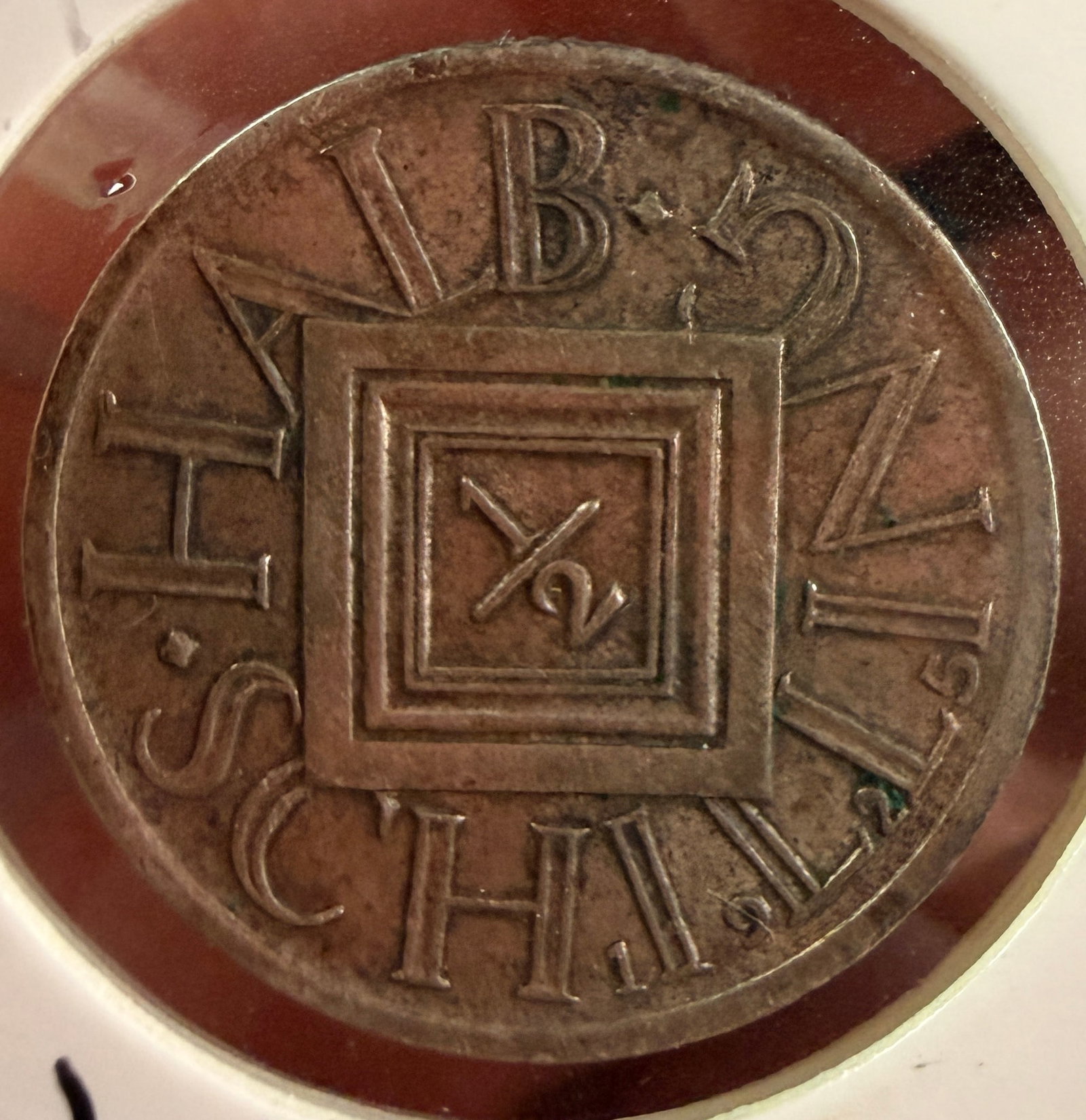 1925 Austria Silver 1/2 Schilling Coin: A Republic of Austria silver 1/2 Schilling coin dated 1925. The coin is composed of .640 silver. The obverse features a central heraldic shield with horizontal hatching set within a square frame,