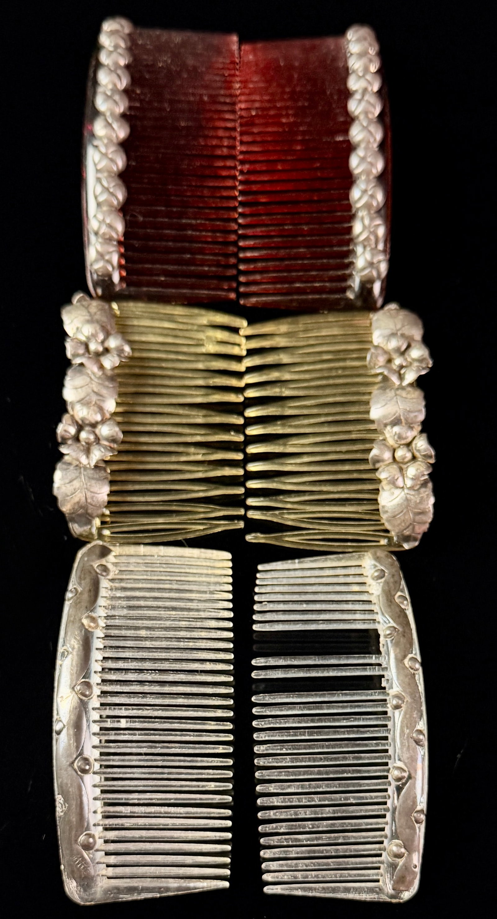 A Collection of Sterling Silver Mounted Hair Side Combs: A collection of six hair side combs, organized into three matching pairs, featuring translucent plastic teeth with decorative sterling silver mounts. The collection includes a pair of dark red combs