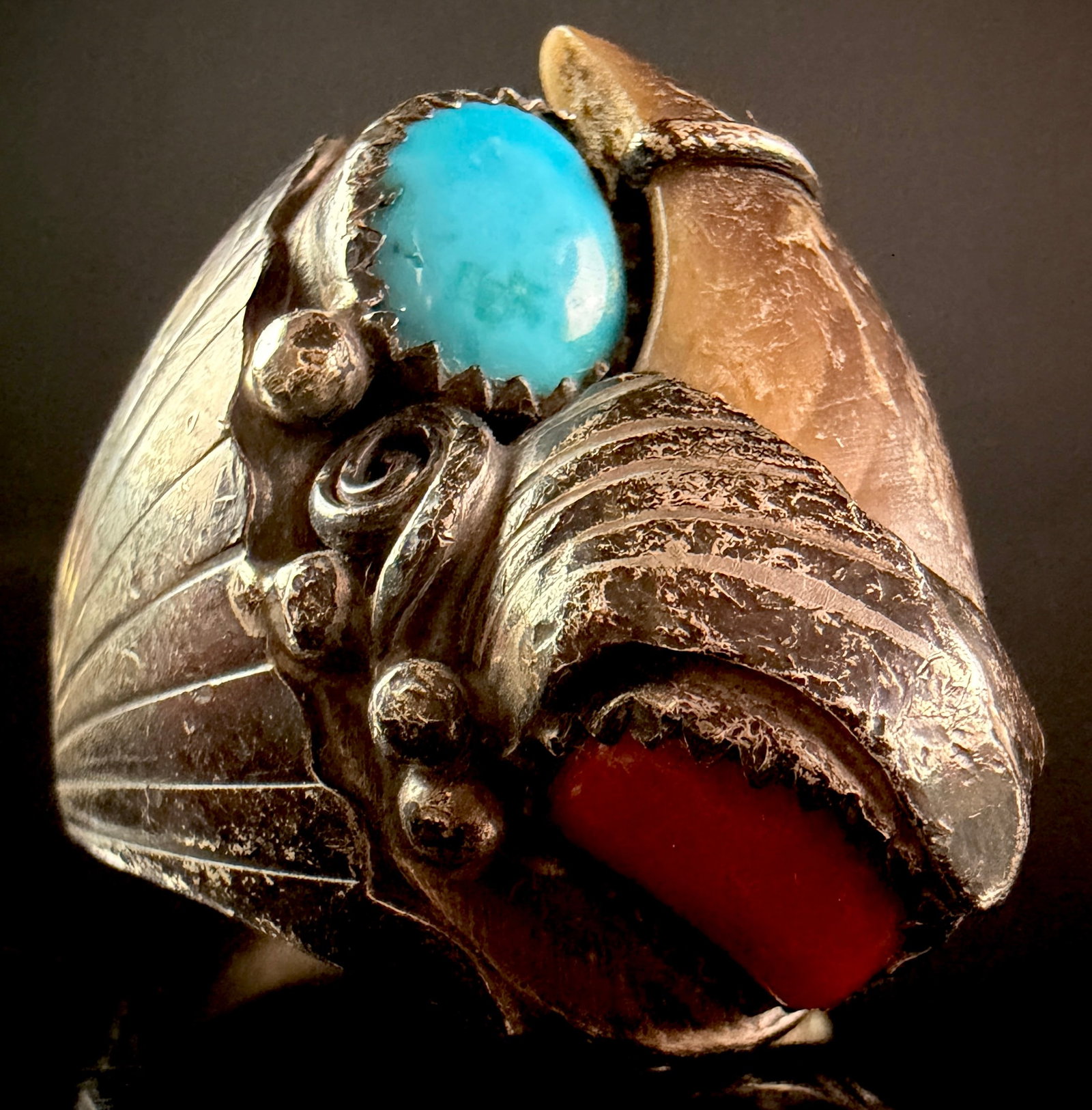 Sterling Silver Southwestern Bear Claw Ring with Turquoise and Coral: A Southwestern style statement ring crafted in sterling silver. The centerpiece is a large, naturally curved bear claw secured within a hand-wrought silver housing featuring an ornate textured cap and