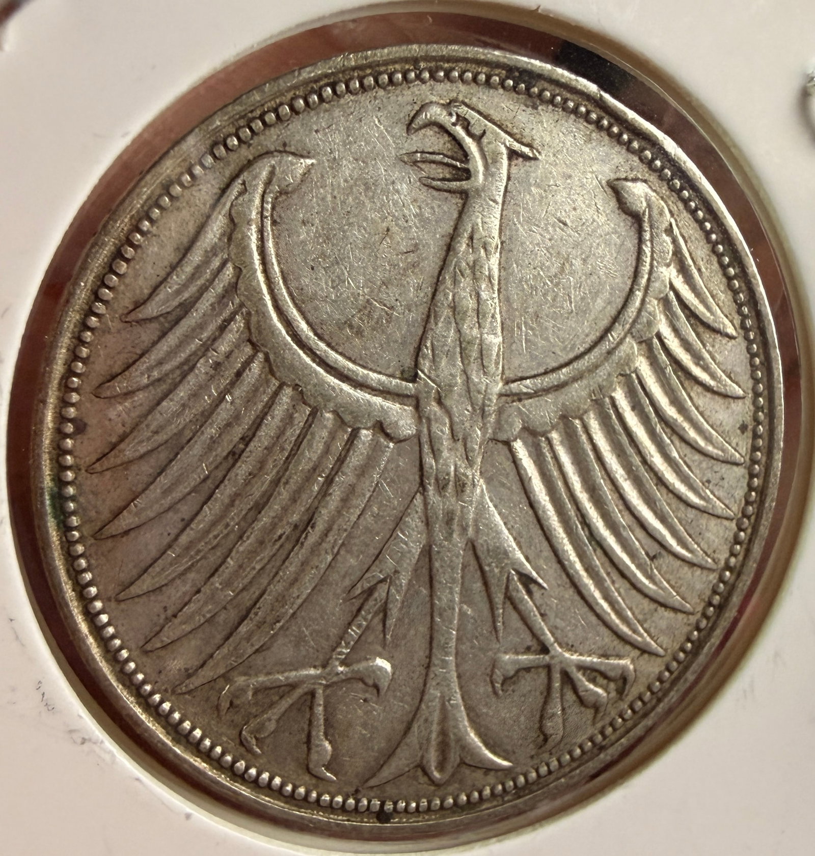 1951 G Federal Republic of Germany Silver 5 Deutsche Mark Coin: This silver coin from the Federal Republic of Germany (Bundesrepublik Deutschland) has a denomination of 5 Deutsche Mark. The obverse features the German Federal Eagle (Bundesadler) facing left with w