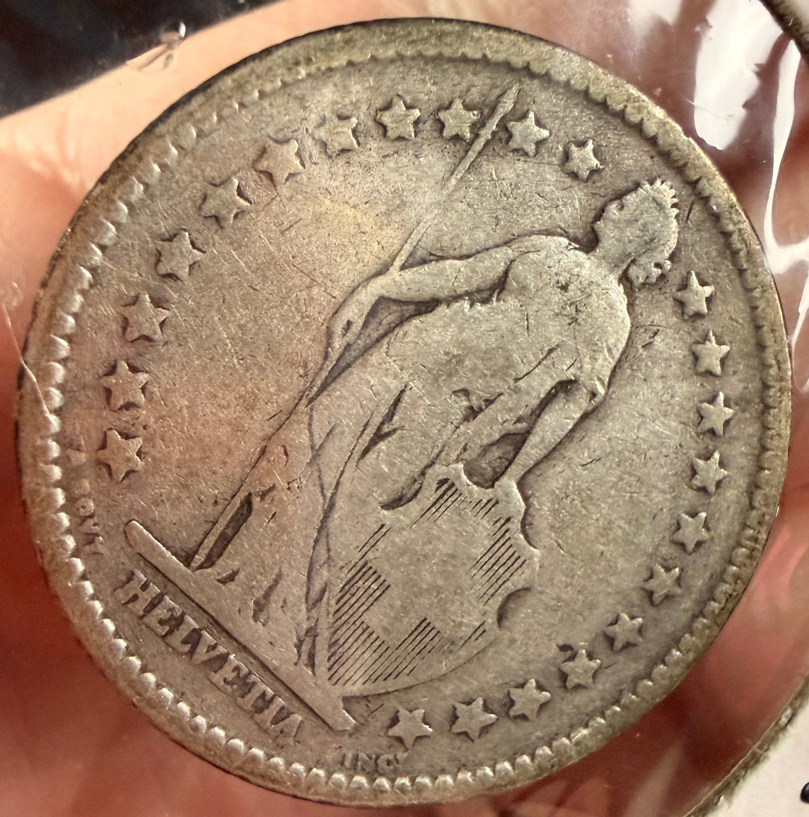 1886 Switzerland 2 Francs Silver Coin: This Swiss 2 Francs silver coin is dated 1886. The obverse displays a standing figure of Helvetia, personifying the Swiss Confederation, draped in robes and holding a spear in her right hand while her