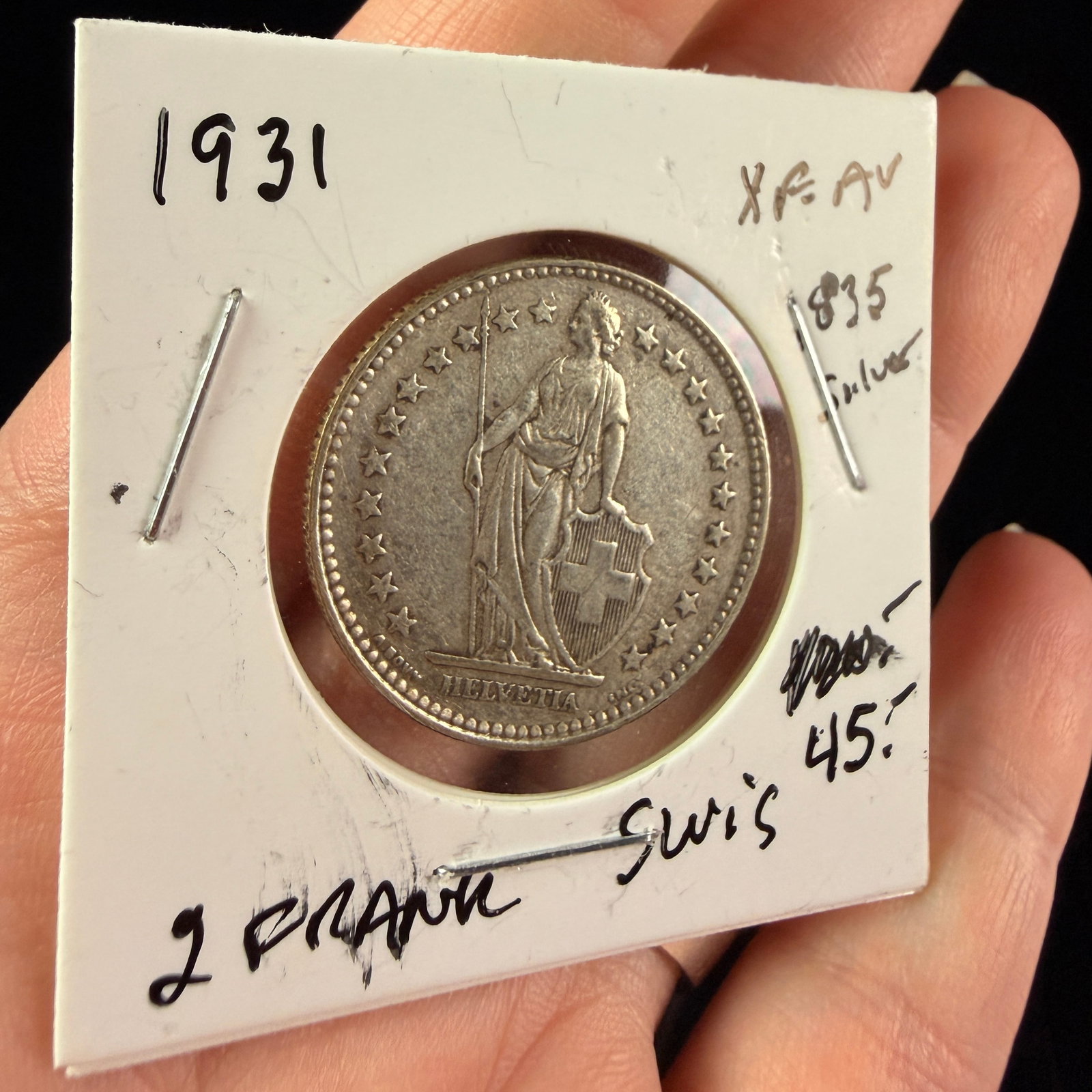 1931 B Switzerland Silver 2 Francs Coin: A 1931 Switzerland silver 2 Francs coin produced at the Bern mint. The obverse features the standing figure of Helvetia facing right, holding a spear and resting her hand on a shield bearing the Swiss