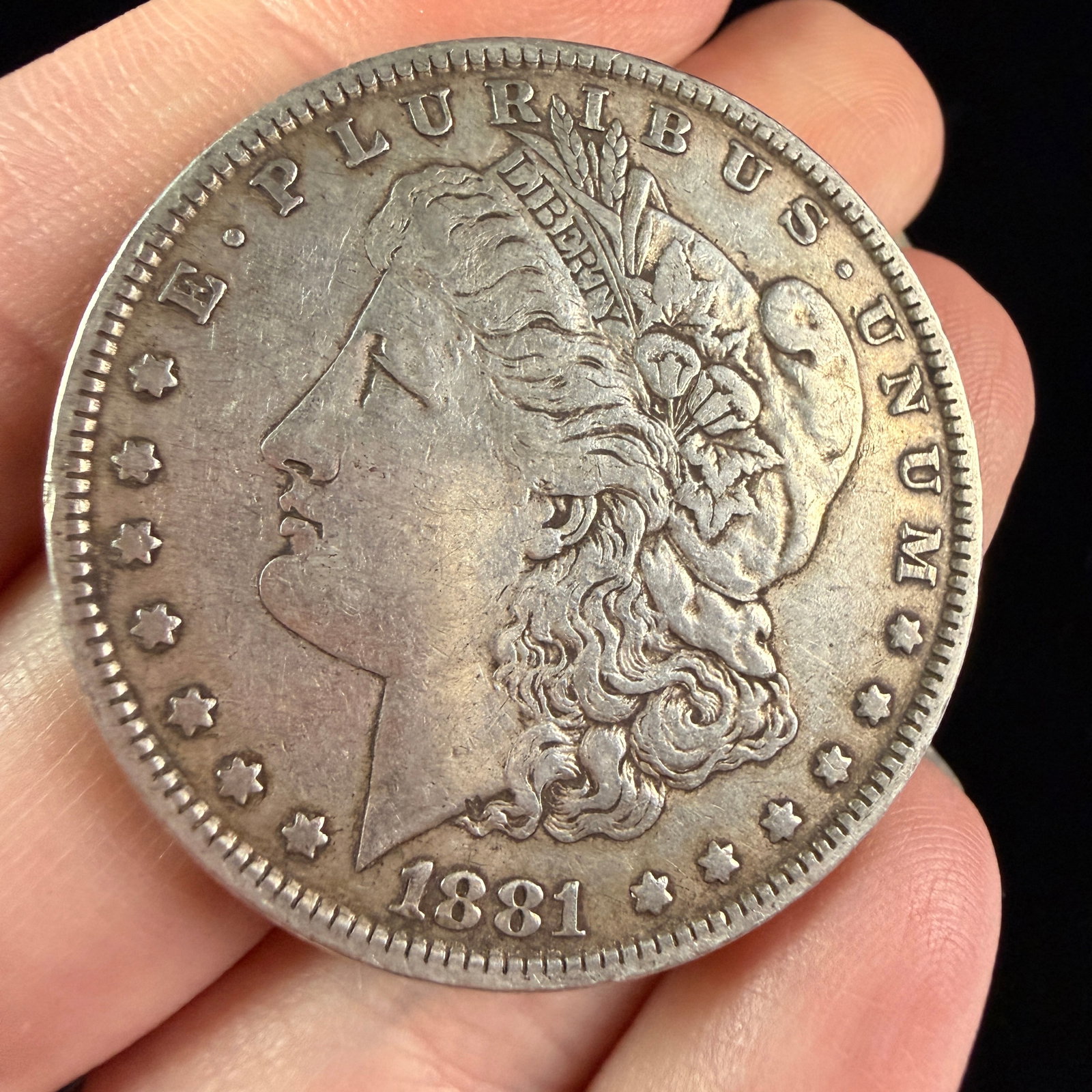 US 1881-S Morgan Silver Dollar: A US Morgan silver dollar dated 1881 and struck in 90% silver. The obverse features the Liberty head design type with the legend E PLURIBUS UNUM, thirteen stars, and the date 1881. The reverse feature