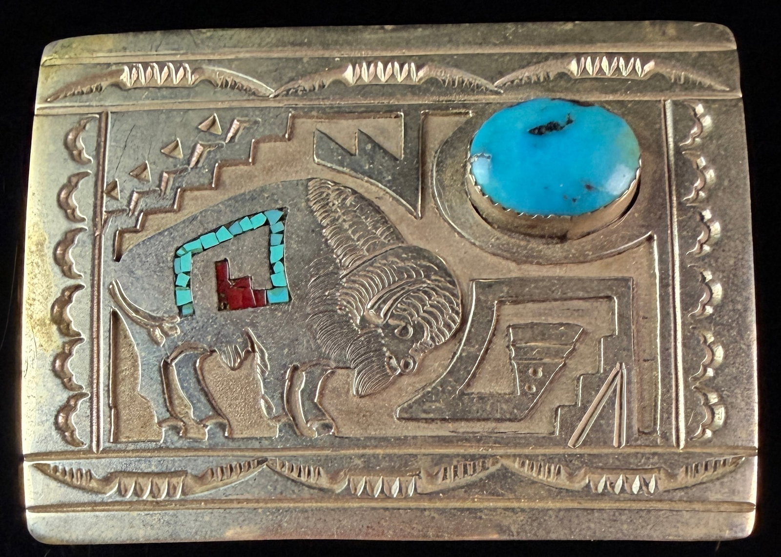 Navajo Sterling Silver and Turquoise Bison Belt Buckle: A Navajo rectangular sterling silver belt buckle featuring a central repouss?© motif of an American bison in profile. The bison is decorated with a rectangular field of turquoise and red stone chip i