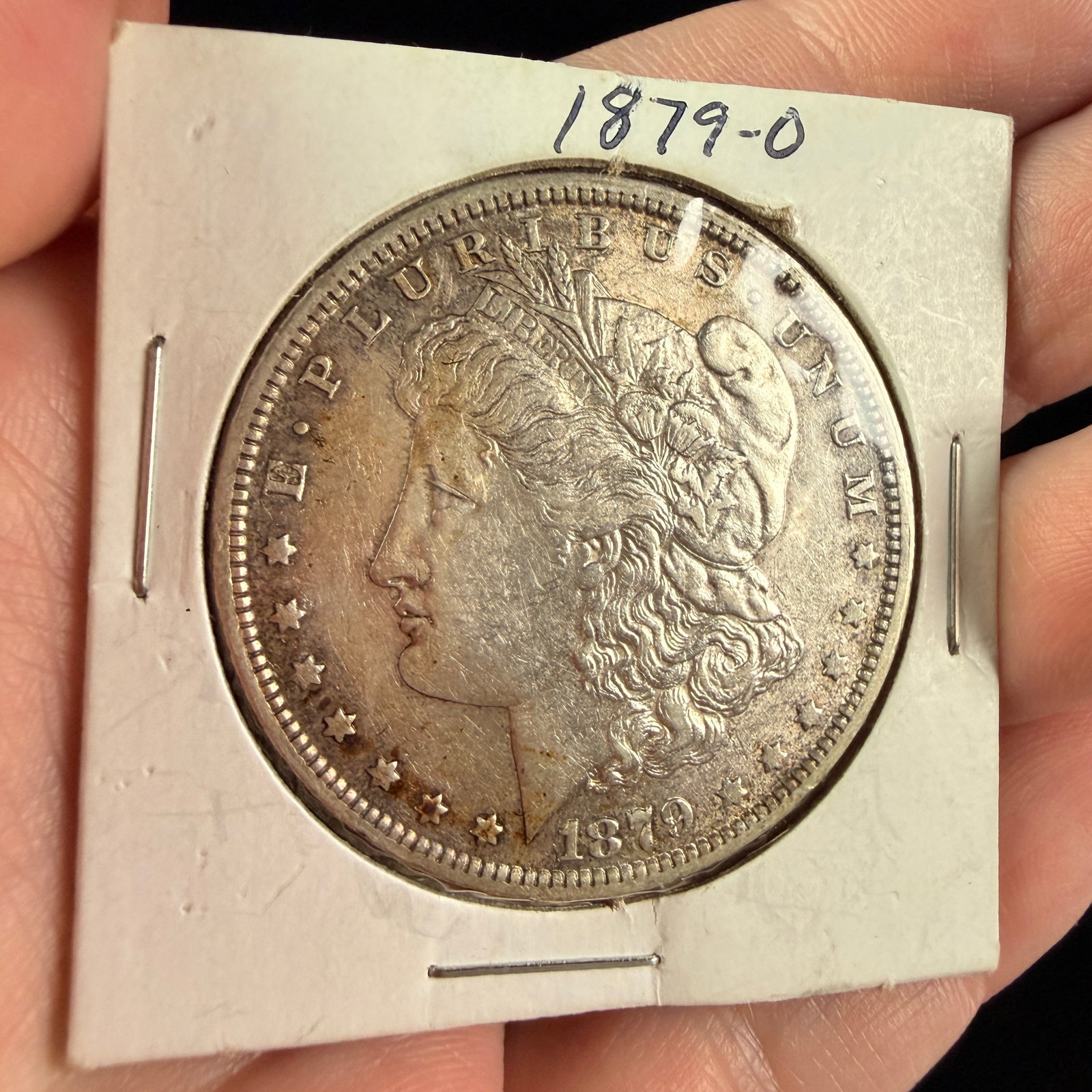 US 1879-O Morgan Silver Dollar: A US silver dollar dated 1879, struck at the New Orleans Mint. The obverse features a left-facing profile of Liberty wearing a cap with the word LIBERTY, surrounded by the legend E PLURIBUS UNUM, thir
