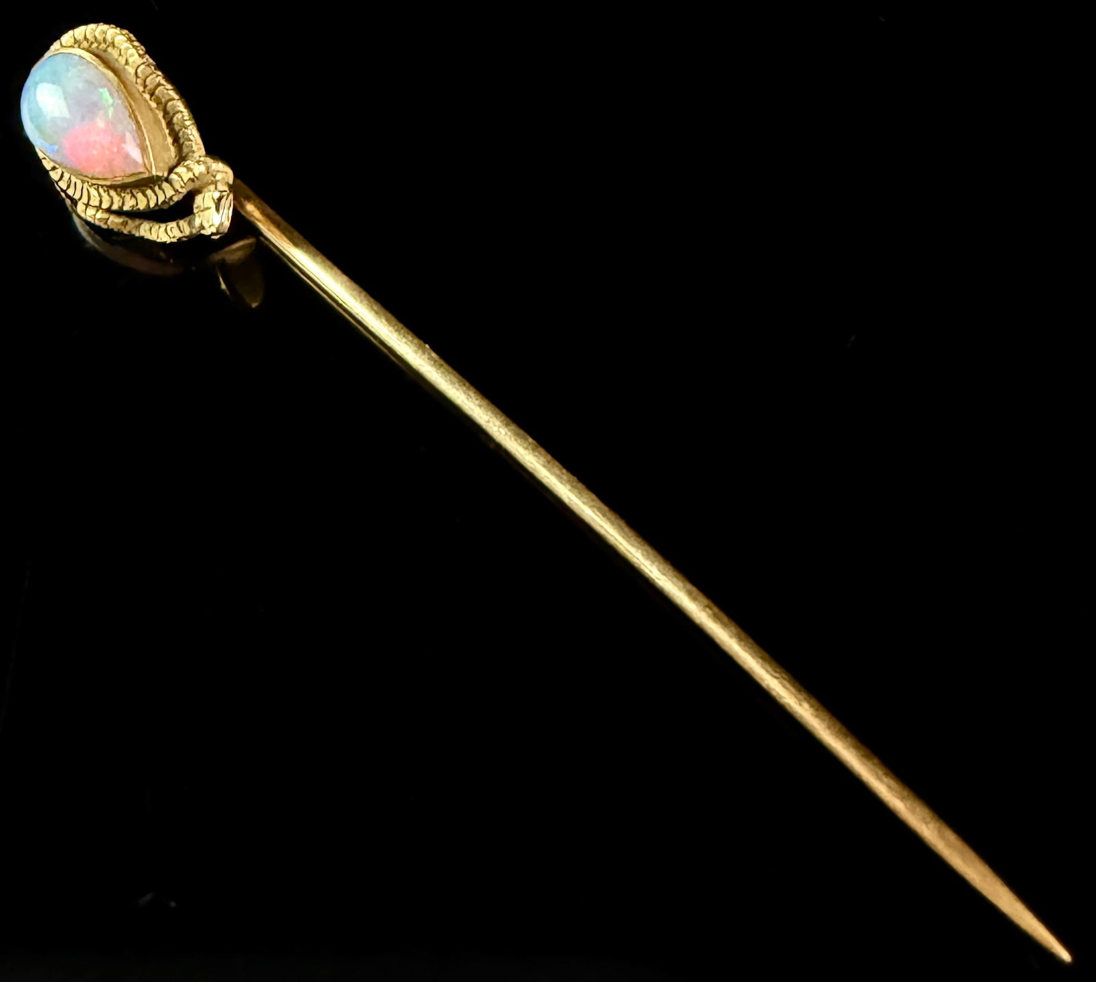14K Yellow Gold Serpent and Opal Stick Pin: An antique-style stick pin crafted from 14K solid yellow gold. The decorative head features a coiled serpent motif, with a textured and scaled body wrapped around a central gemstone. The serpent head