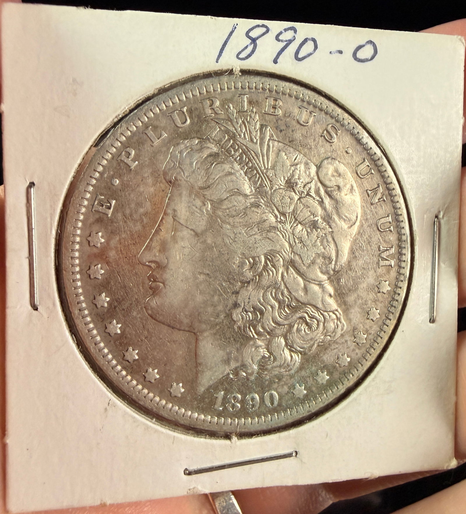 US 1890-O Morgan Silver Dollar: A US 1890-O Morgan silver dollar. The obverse bears the date 1890 and the motto E PLURIBUS UNUM with thirteen stars, while a tiara is inscribed with the word LIBERTY. The reverse features the legends
