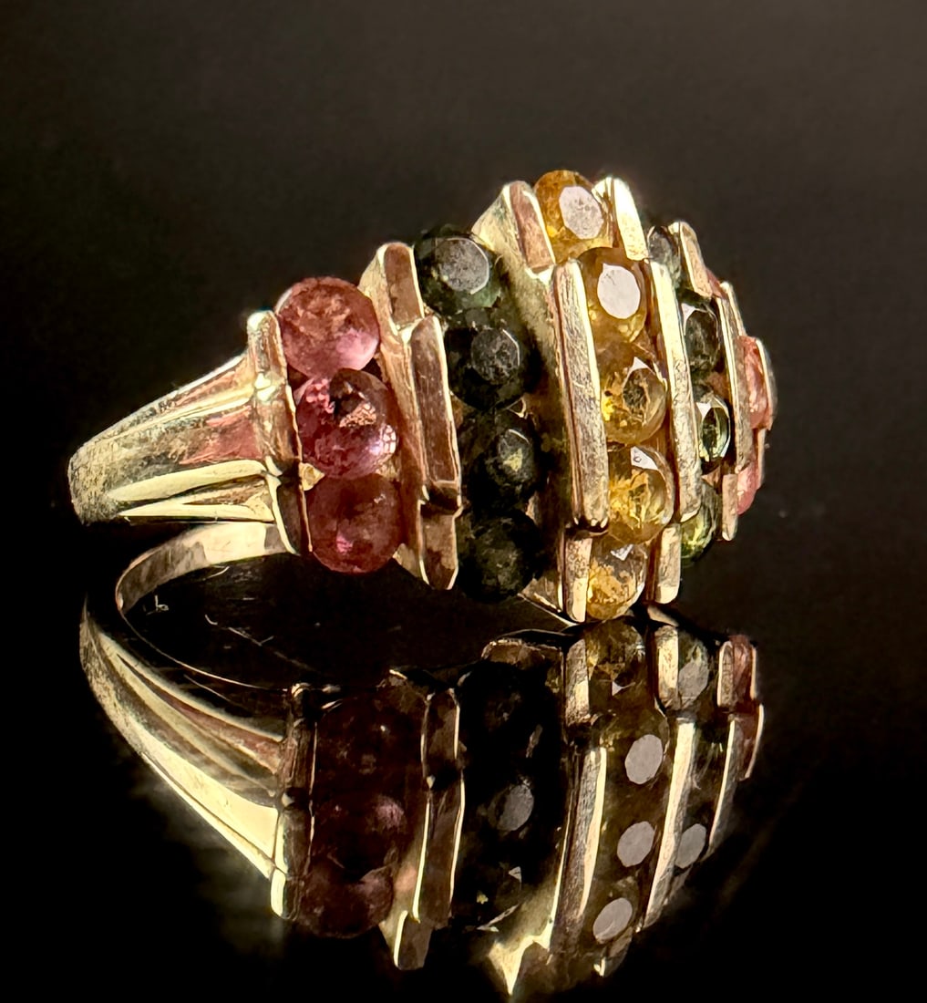 Multi-Gemstone 10K Yellow Gold Tiered Bar Cocktail Ring: A cocktail ring constructed from 10K solid yellow gold. The piece features a tiered, architectural design composed of five vertical rows of round faceted gemstones separated by polished yellow gold
