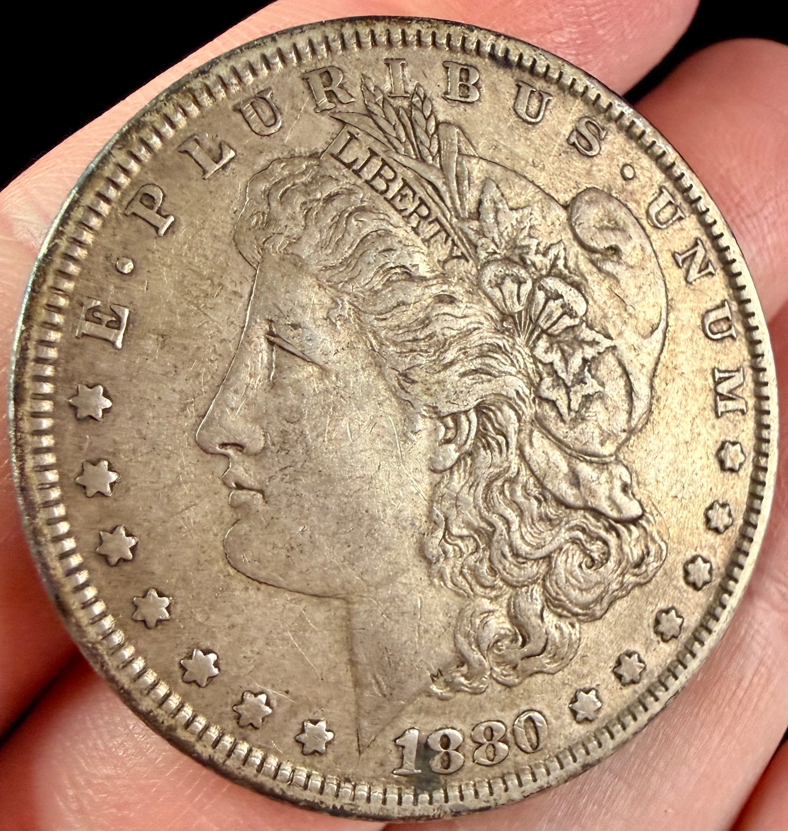 1880 US Morgan Silver Dollar: A 1880 US silver dollar of the Morgan type, struck at the Philadelphia Mint. The obverse is inscribed E PLURIBUS UNUM along the top border, LIBERTY on the headband, and 1880 at the base. The reverse i