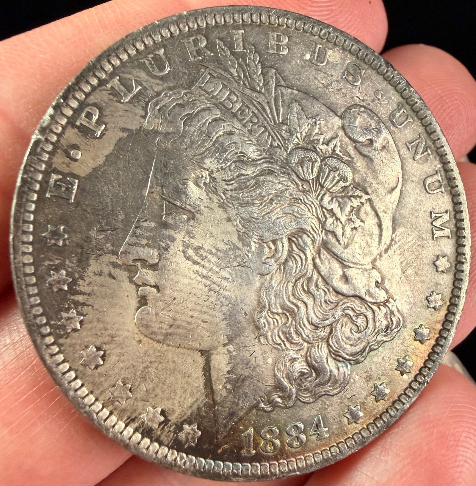 1884-O US Morgan Silver Dollar: A US Morgan silver dollar minted in 1884. The coin is struck in 90% silver and 10% copper. An impressed O mint mark is located on the reverse, positioned above the DO in DOLLAR, identifying it as a