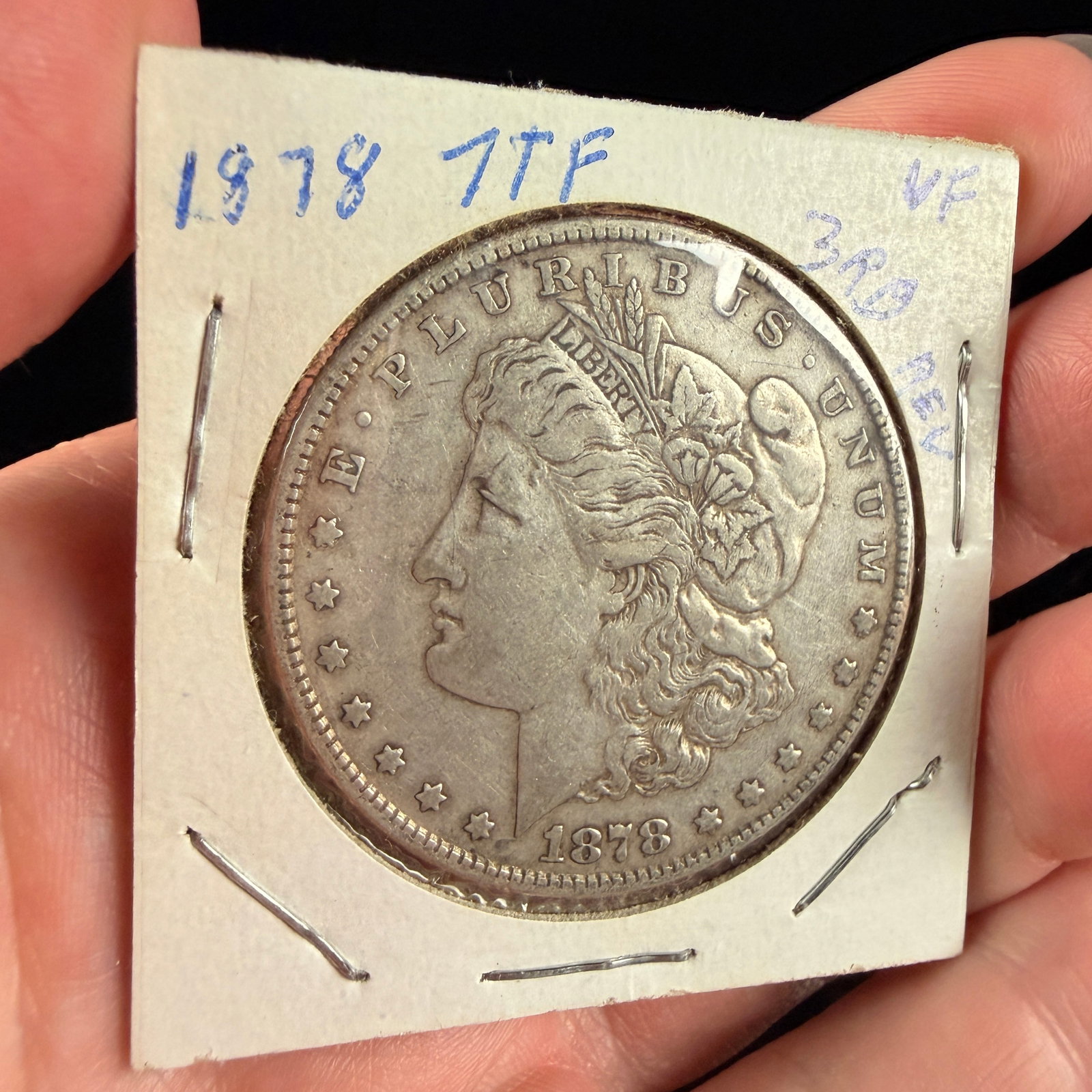 US 1878 One Dollar Morgan Silver Coin 7 Tail Feathers Third Reverse Variety: A US 1878 silver dollar struck at the Philadelphia Mint, featuring the Morgan design. This specific example is the 7 Tail Feathers, Third Reverse variety, also identified as the Slanting Arrow Feather