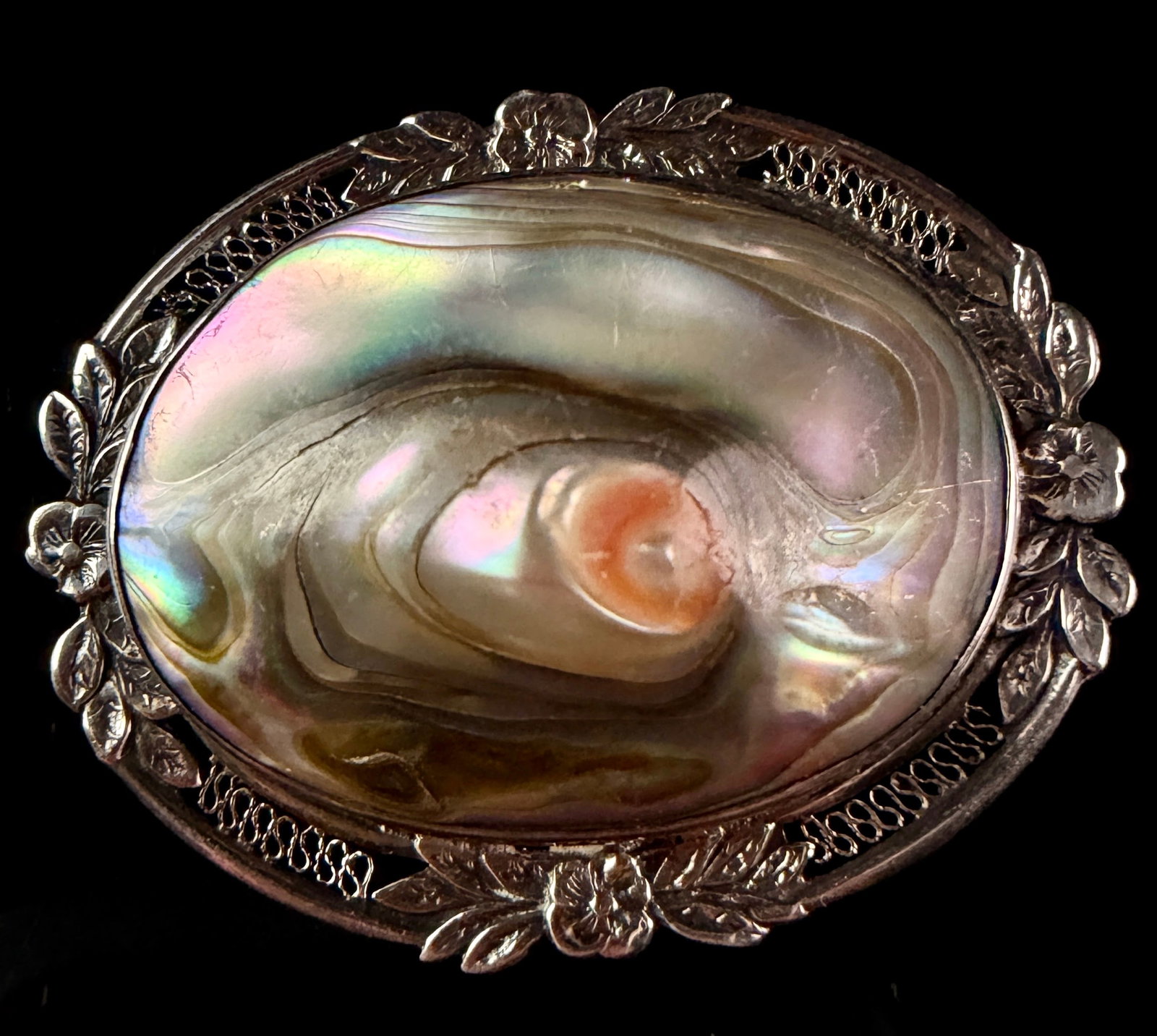 Vintage Sterling Silver and Abalone Shell Floral Openwork Brooch: A vintage sterling silver brooch featuring a large, domed oval abalone shell cabochon. The shell exhibits vibrant pink, green, and blue iridescence with a prominent natural peach-colored eye or bliste