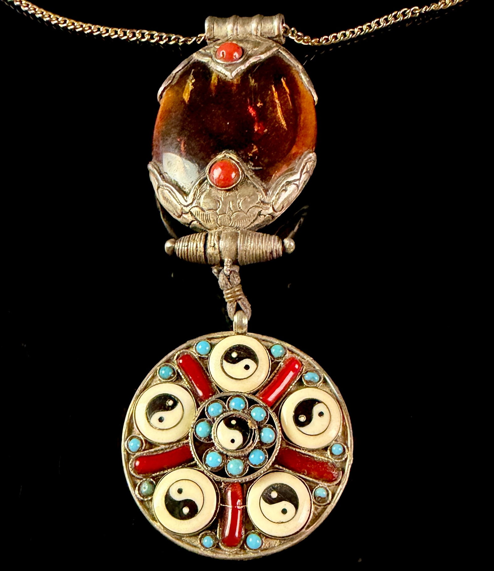 Tibetan Style Articulated Silver Toned Pendant Necklace with Amber Coral and Turquoise: A large two-part articulated pendant necklace in a Himalayan tribal style. The necklace features a silver-toned flat snake chain supporting a multi-material pendant. The upper portion of the pendant