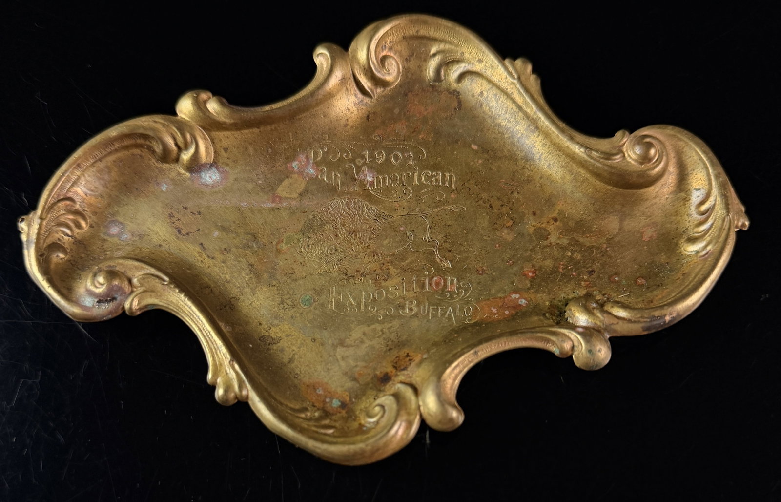 Art Nouveau Gilt Brass 1901 Pan-American Exposition Buffalo Souvenir Tray: A commemorative Art Nouveau pin tray or dresser dish manufactured from gilt brass. The tray features an elaborate cast border of asymmetrical Rococo-style scrolling flourishes. The central well is sta