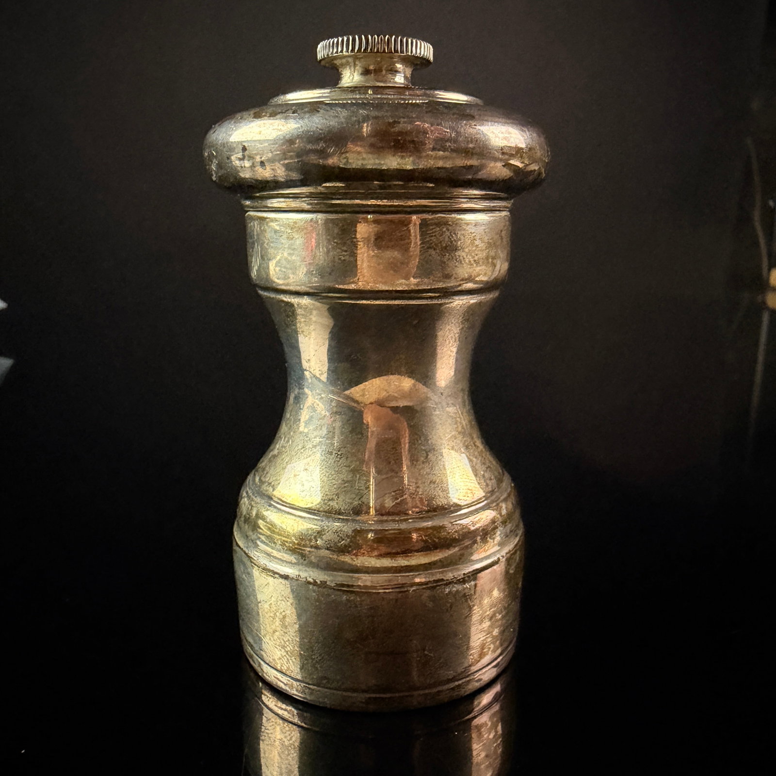 Sterling Silver French Pepper Mill: A sterling silver French pepper mill of baluster form featuring a waisted central section and a stepped base. The top is surmounted by a circular knurled adjusting nut. The piece is constructed with
