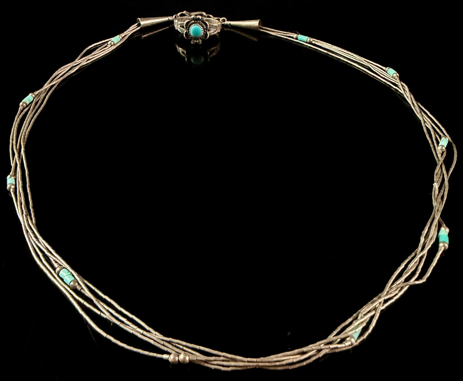 A Navajo Lot of Sterling Silver and Turquoise Jewelry Comprising a Multi-Strand Necklace and a: This Navajo lot includes a multi-strand necklace and a statement ring, both crafted from sterling silver with turquoise embellishments. The necklace is constructed with five strands of fine tubular li