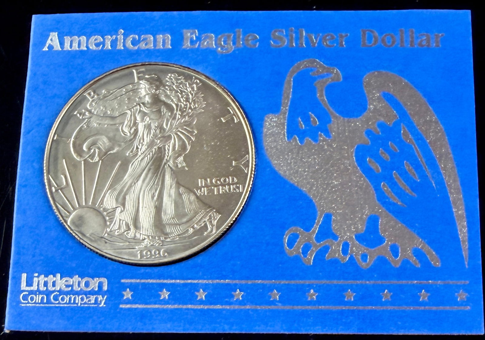 1996 US American Eagle One Ounce Silver Dollar in Littleton Coin Company Packaging: A 1996 US American Eagle one-dollar bullion coin struck in one troy ounce of .999 fine silver. The obverse displays the Walking Liberty design with inscriptions reading LIBERTY, IN GOD WE TRUST, and t