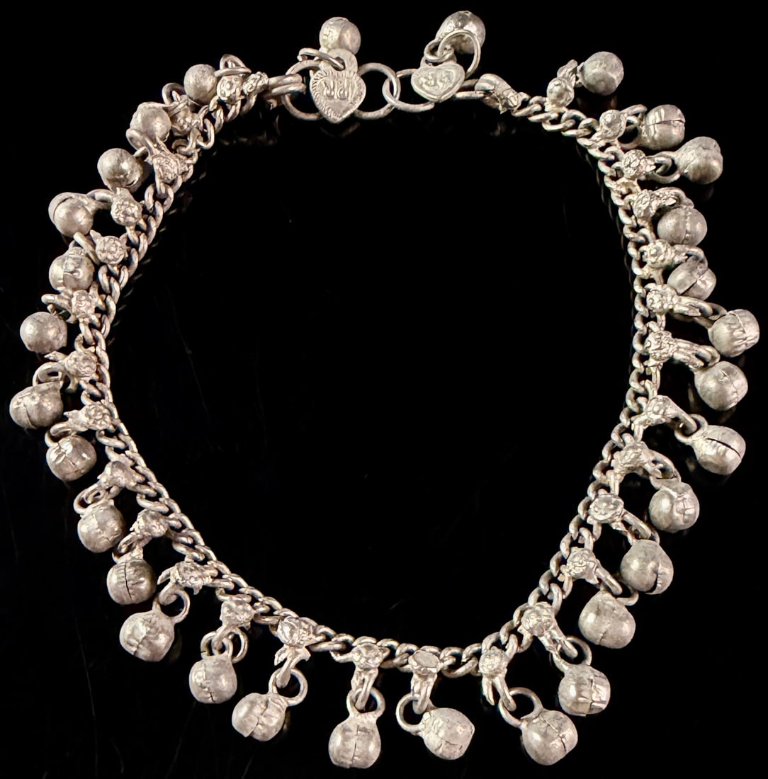 A Silver Ethnic Curb Link Bell Fringe Anklet: An ethnic silver jewelry piece featuring a heavy curb-link chain densely adorned with numerous spherical drop bells. The construction displays characteristics of traditional casting with slight irregu