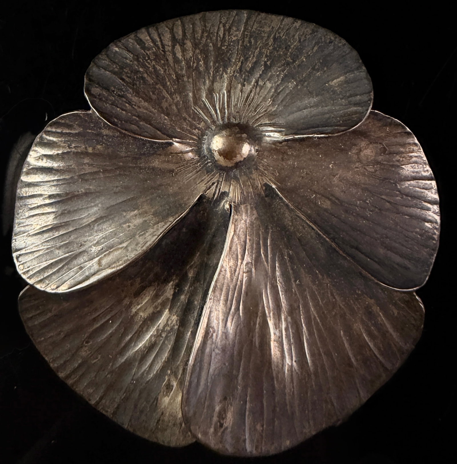 Vintage Sterling Silver Pansy Flower Brooch: A sterling silver brooch modeled as a pansy blossom with five petals. Each petal features a hand-hammered radial texture, and the center is finished with a raised dome. The petals are joined at the ce