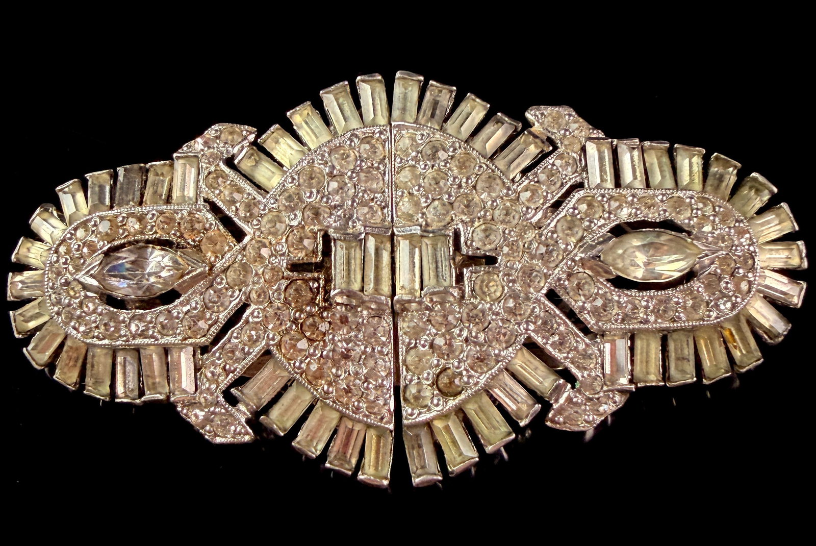 Art Deco Rhinestone Convertible Clip-Brooch: An Art Deco period convertible clip-brooch consisting of two matching dress clips mounted to a single pin-back frame. The assembly features a symmetrical geometric shield design with a starburst