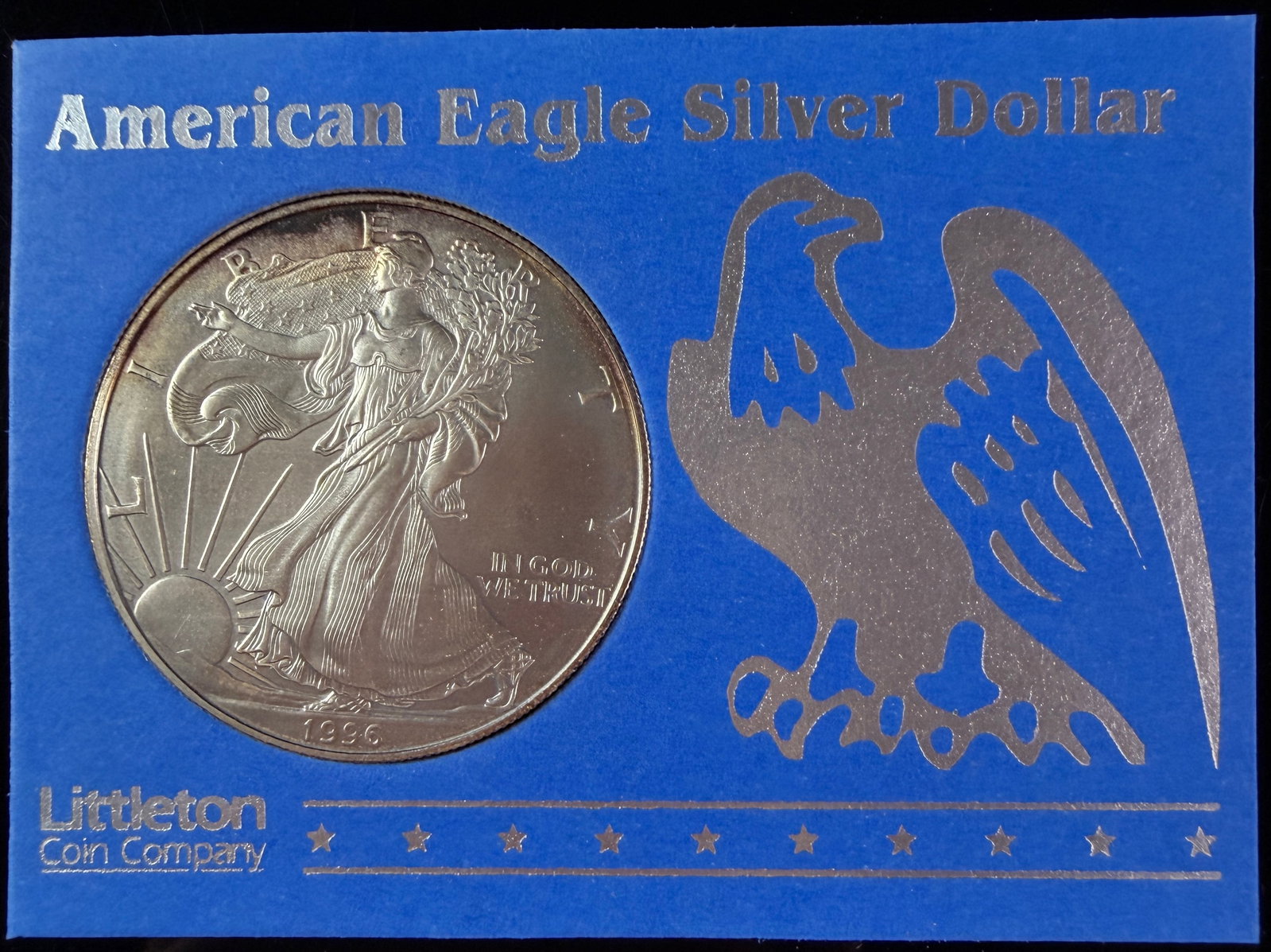 1996 US American Eagle One Dollar Silver Bullion Coin in Littleton Coin Company Holder: A 1996 United States American Eagle one-dollar silver bullion coin. This coin is struck in one troy ounce of fine silver, with a composition of 99.93 percent silver and less than 1 percent copper. The