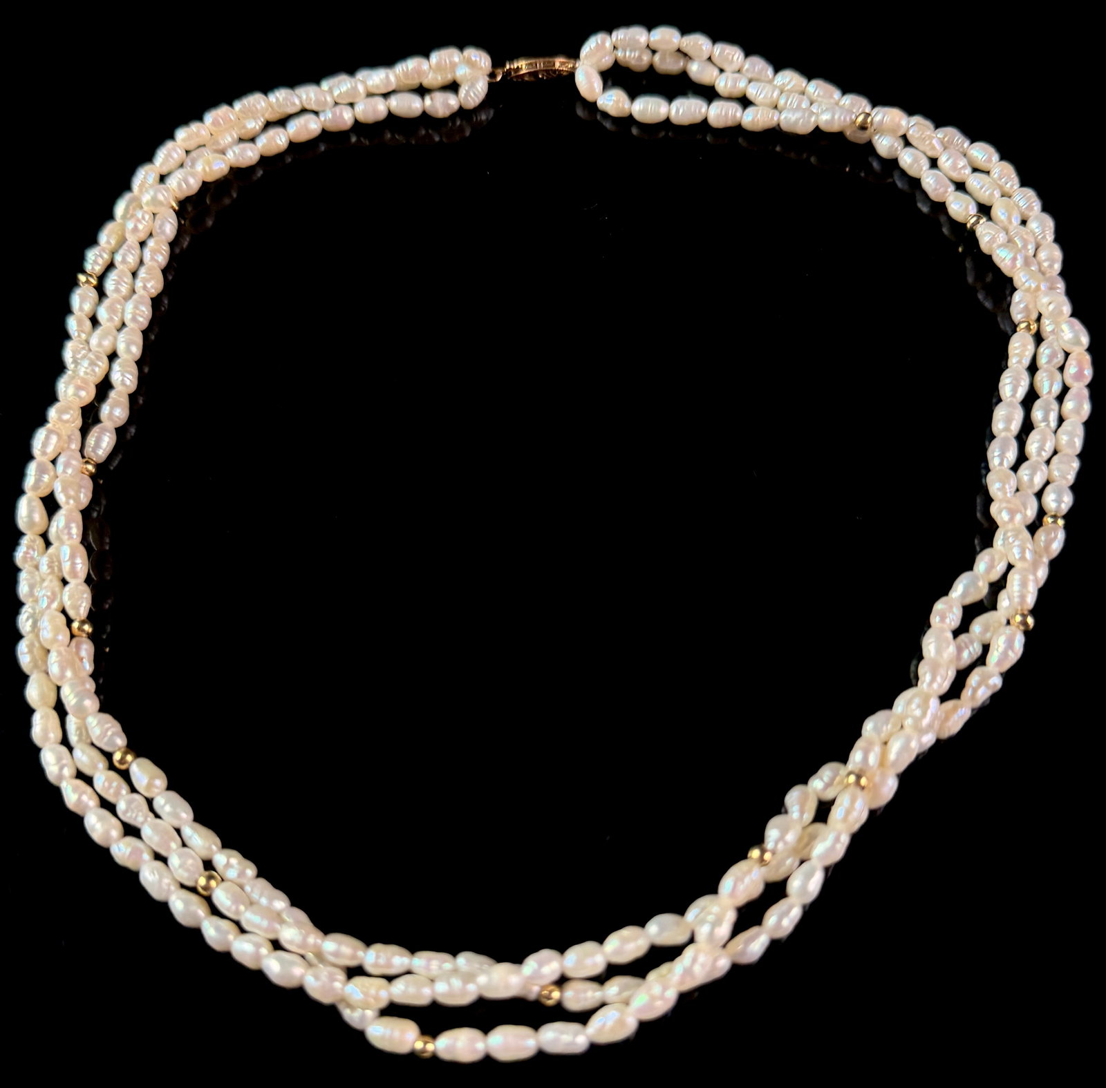 Triple-Strand Freshwater Cultured Pearl and 14 Karat Yellow Gold Bead Necklace: A three-strand necklace featuring white freshwater cultured pearls and 14 karat yellow gold accents. The necklace is composed of three strands of small, baroque-shaped white pearls that exhibit high l