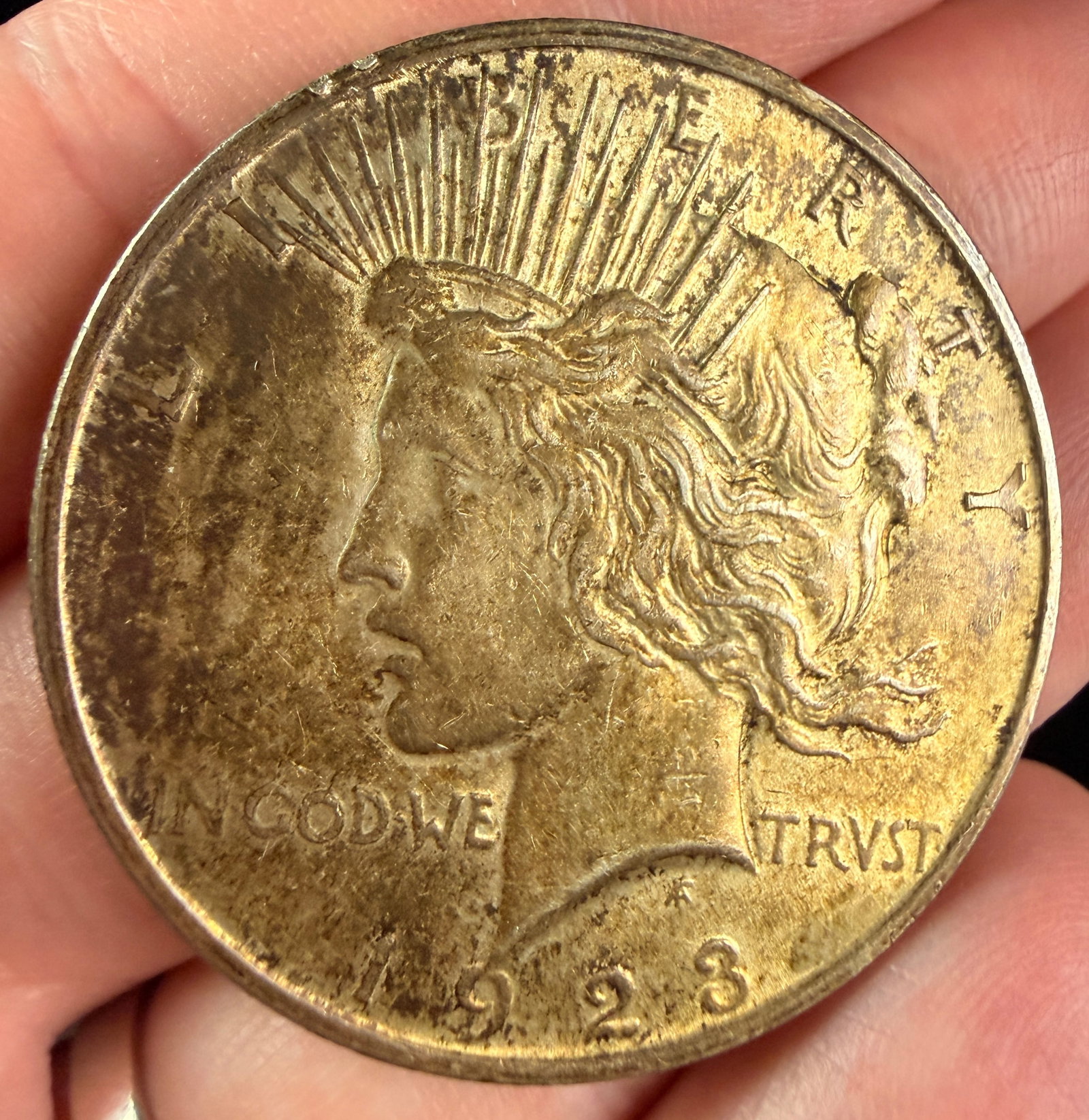 1923 US Peace Silver Dollar: A 1923 United States Peace silver dollar. The coin is struck in a composition of 90% silver and 10% copper at the Philadelphia Mint. The obverse features a left-facing profile of Liberty wearing a rad