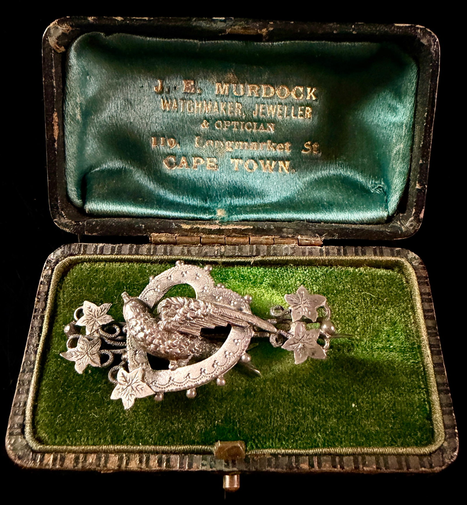 Edwardian Sterling Silver Bird Heart and Ivy Sweetheart Brooch in Original Retailer Box 1901: An Edwardian sterling silver sweetheart brooch featuring a central heart shaped wreath motif with a bird in flight at its center. The heart is decorated with a granulated bead border and sits above a