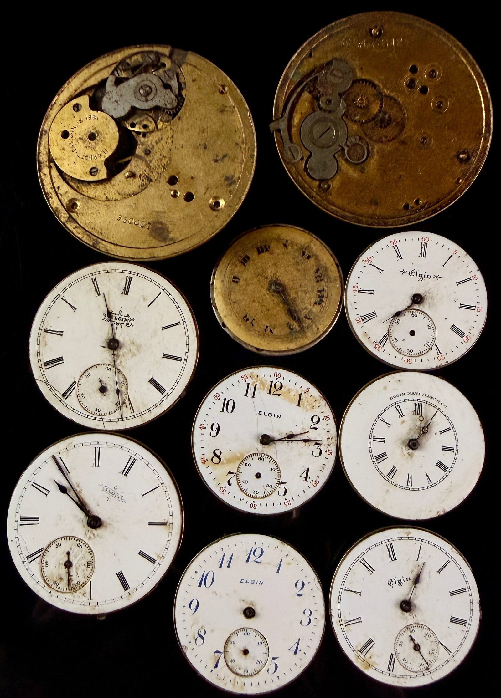 A Collection of Antique Elgin National Watch Co. Pocket Watch Movements and Dials: A collection of manual wind antique pocket watch movements and dials primarily produced by the Elgin National Watch Co. The group features movements with various finishes including brass-gilt and nick