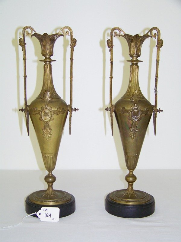 Pair Early Bronze Patinated Figural Urns: With figures to handles and front and back . Both with double handles on marble bases . Stand app. 15" tall3 1/2" wide at base of urn . Used as candle holders.
