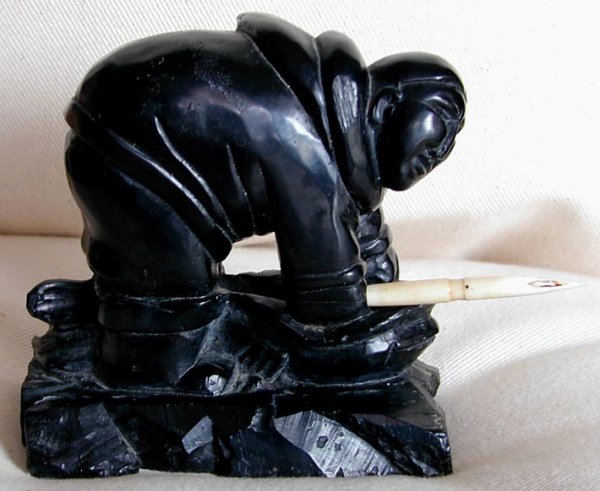 INUIT ARGILLITE CARVING: This Inuit argillite carving of an Inuit hunter with a spear made of walrus tusk ivory. It is 4 1/2" high and 6" wide